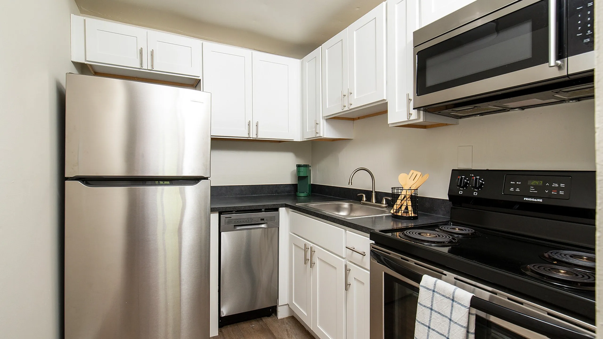 Modern kitchen with sleek stainless steel appliances, elegant white cabinetry, and stylish dark countertops for a contemporary look.