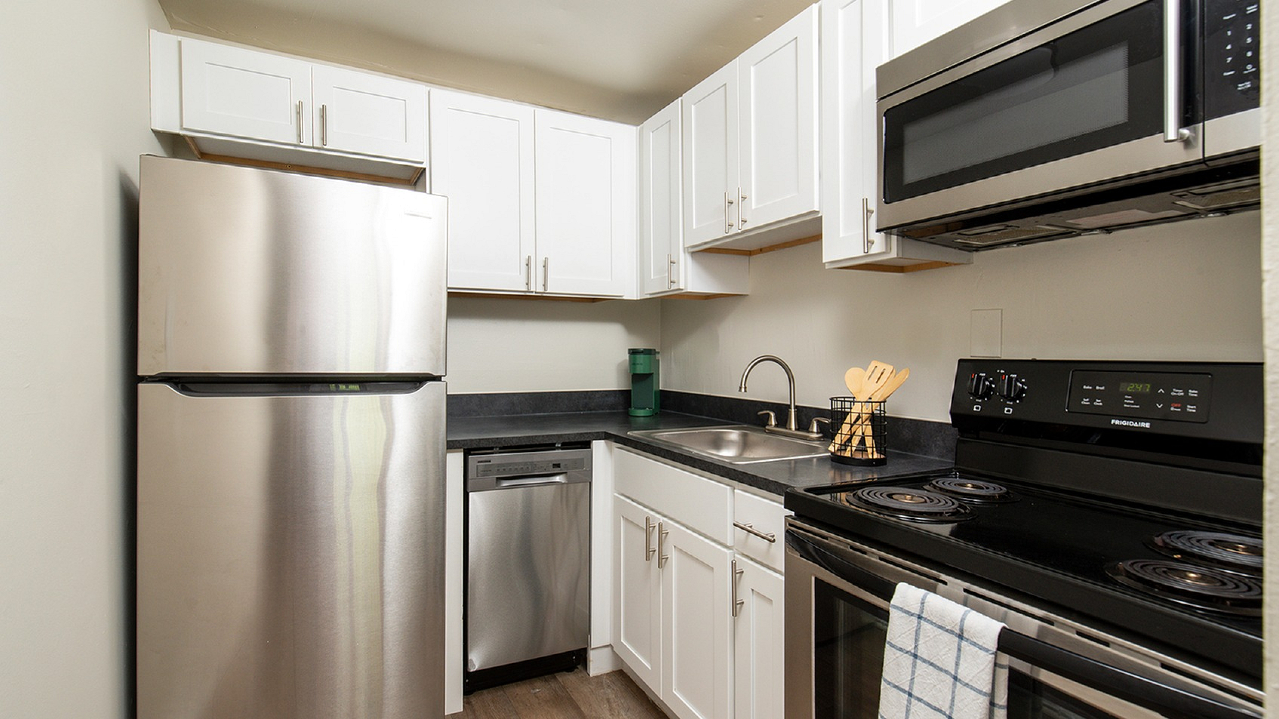 Contemporary kitchen with stainless steel appliances, sleek white cabinets, and elegant black countertops.