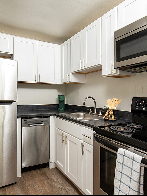 Modern kitchen with sleek stainless steel appliances, elegant white cabinetry, and stylish wood flooring.
