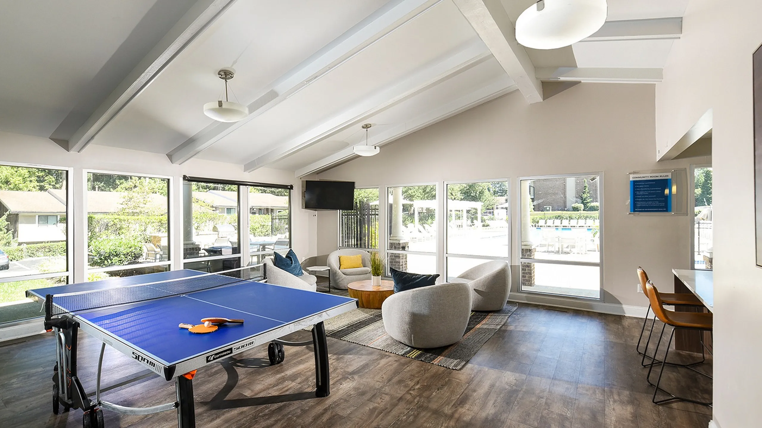 Bright recreational room featuring a sleek ping pong table, cozy seating area, and large windows with scenic views.