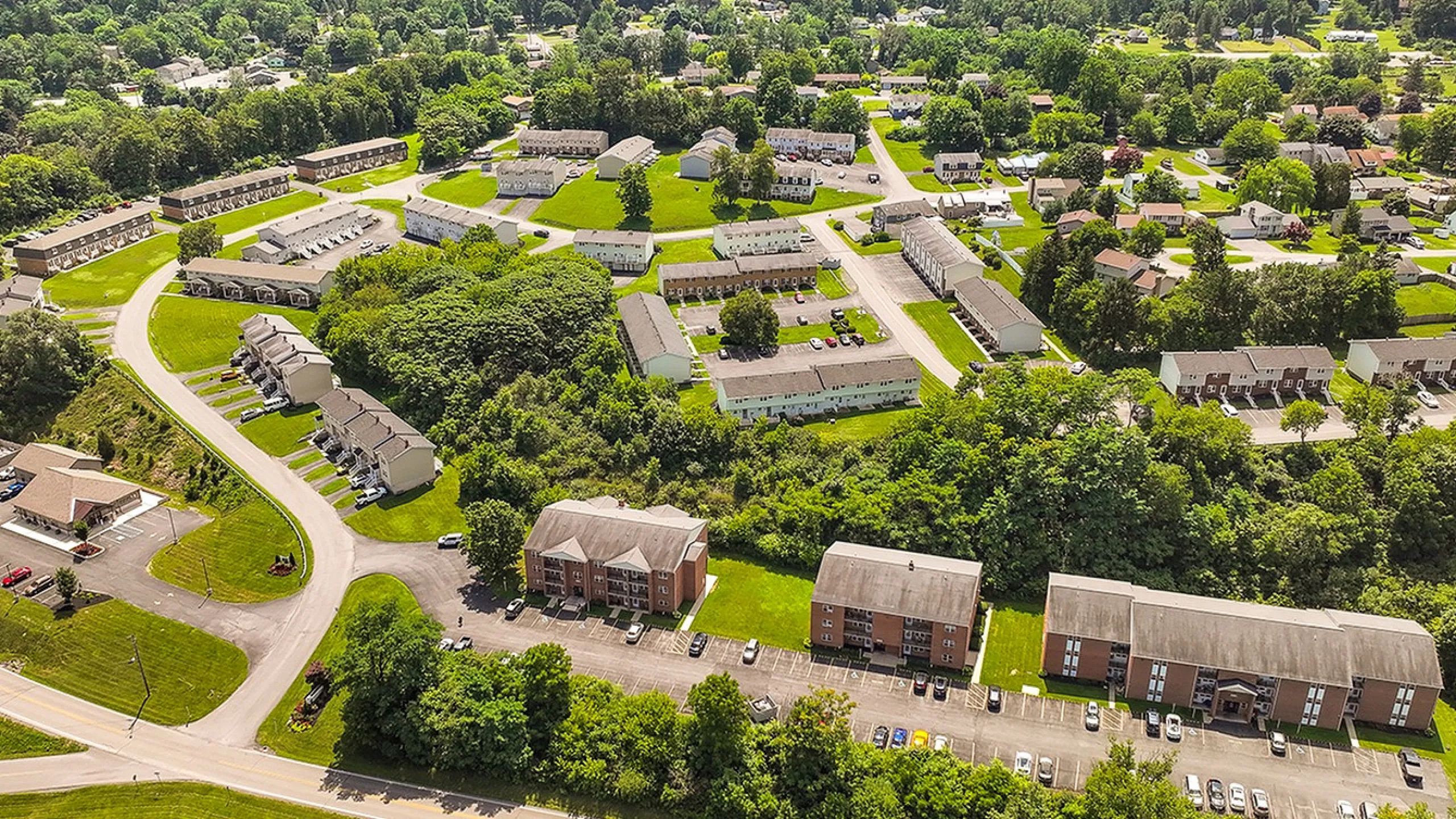 Scenic aerial view of a lush, green neighborhood showcasing modern apartment complexes surrounded by vibrant trees and well-maintained pathways.