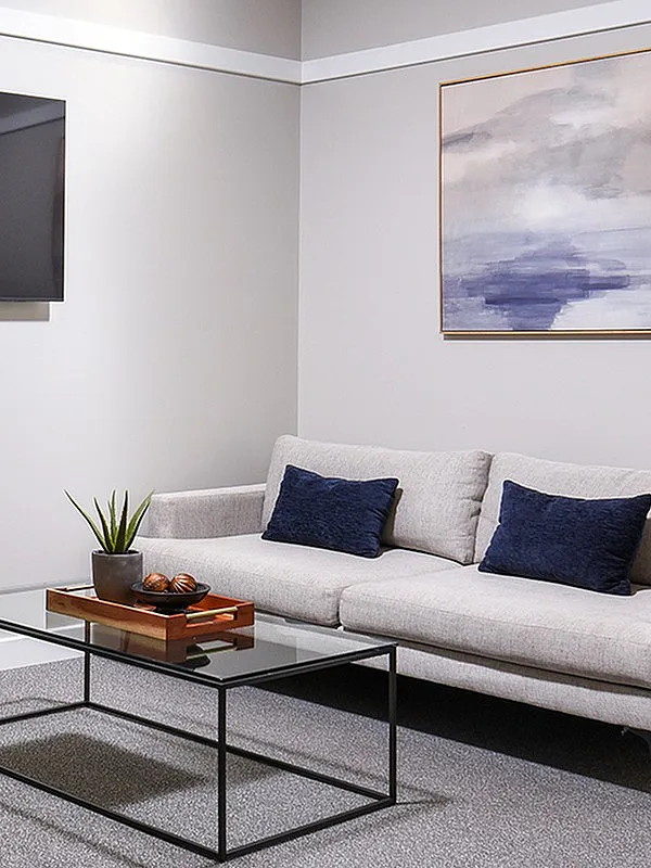 Modern living room with a sleek gray sofa, leather chairs, and a glass coffee table, creating a stylish and inviting atmosphere.