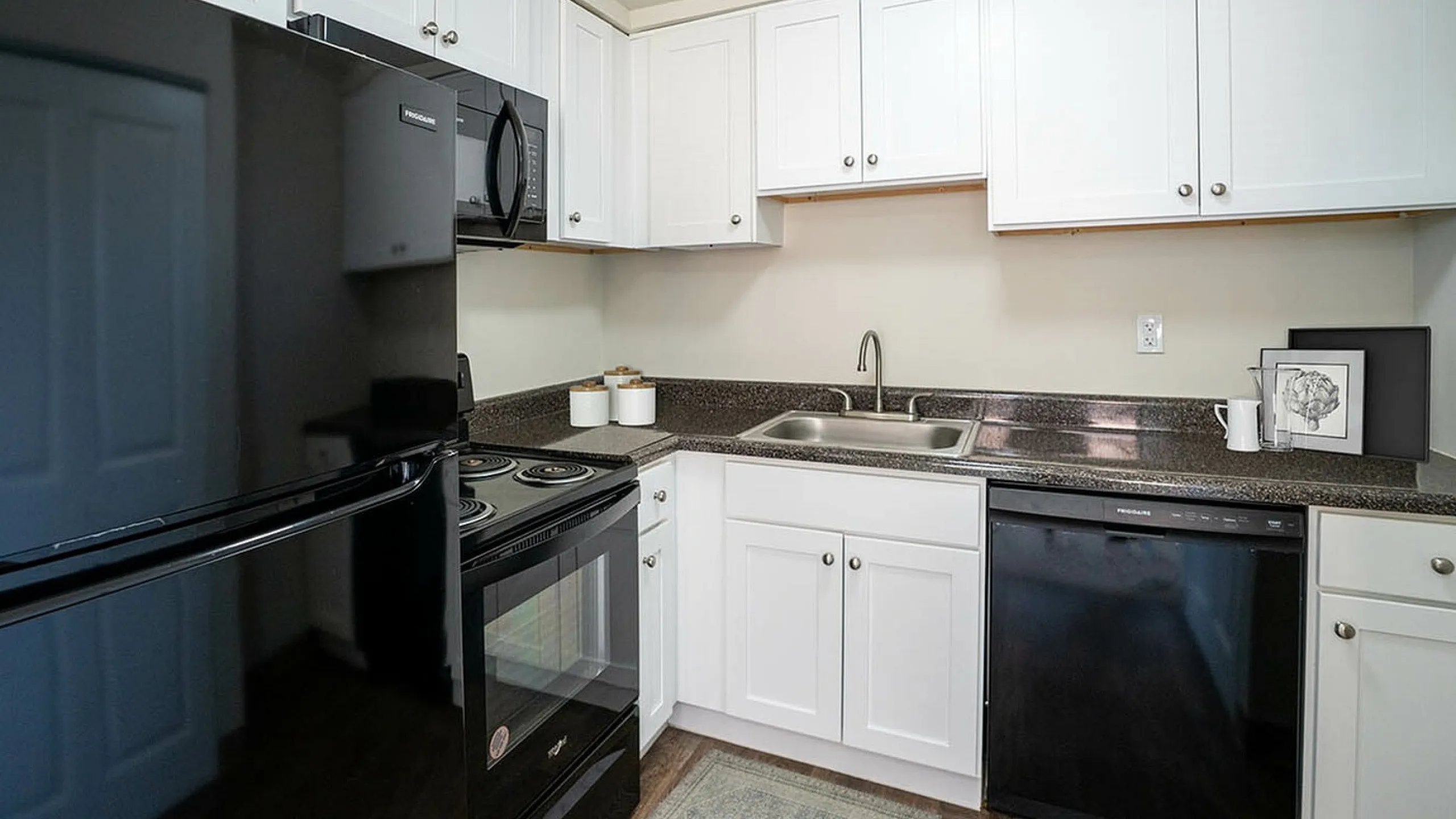 Modern kitchen with sleek black appliances, white cabinetry, and elegant dark countertops.