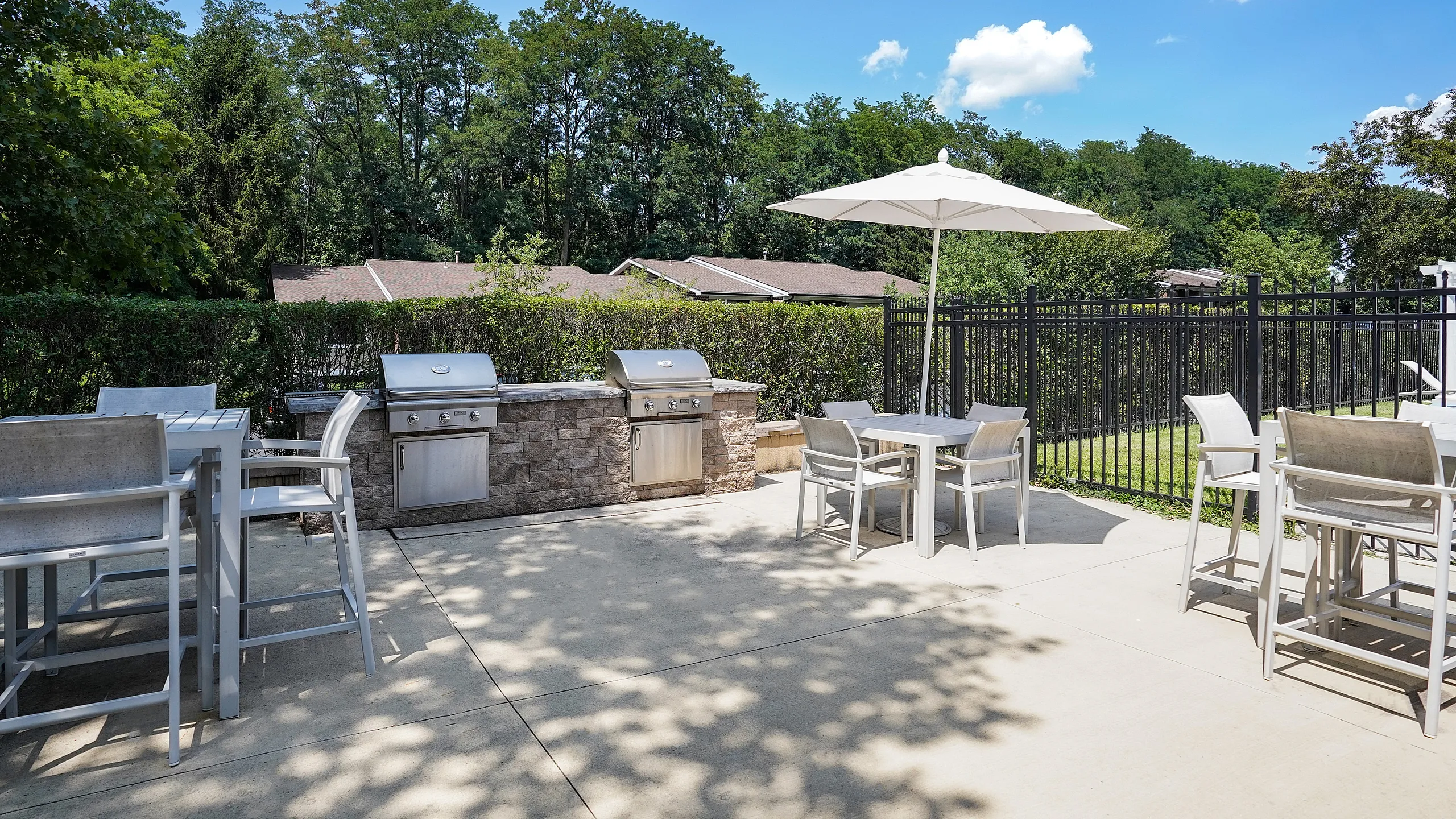 Inviting outdoor patio with modern grills, stylish seating, and lush greenery, perfect for entertaining.