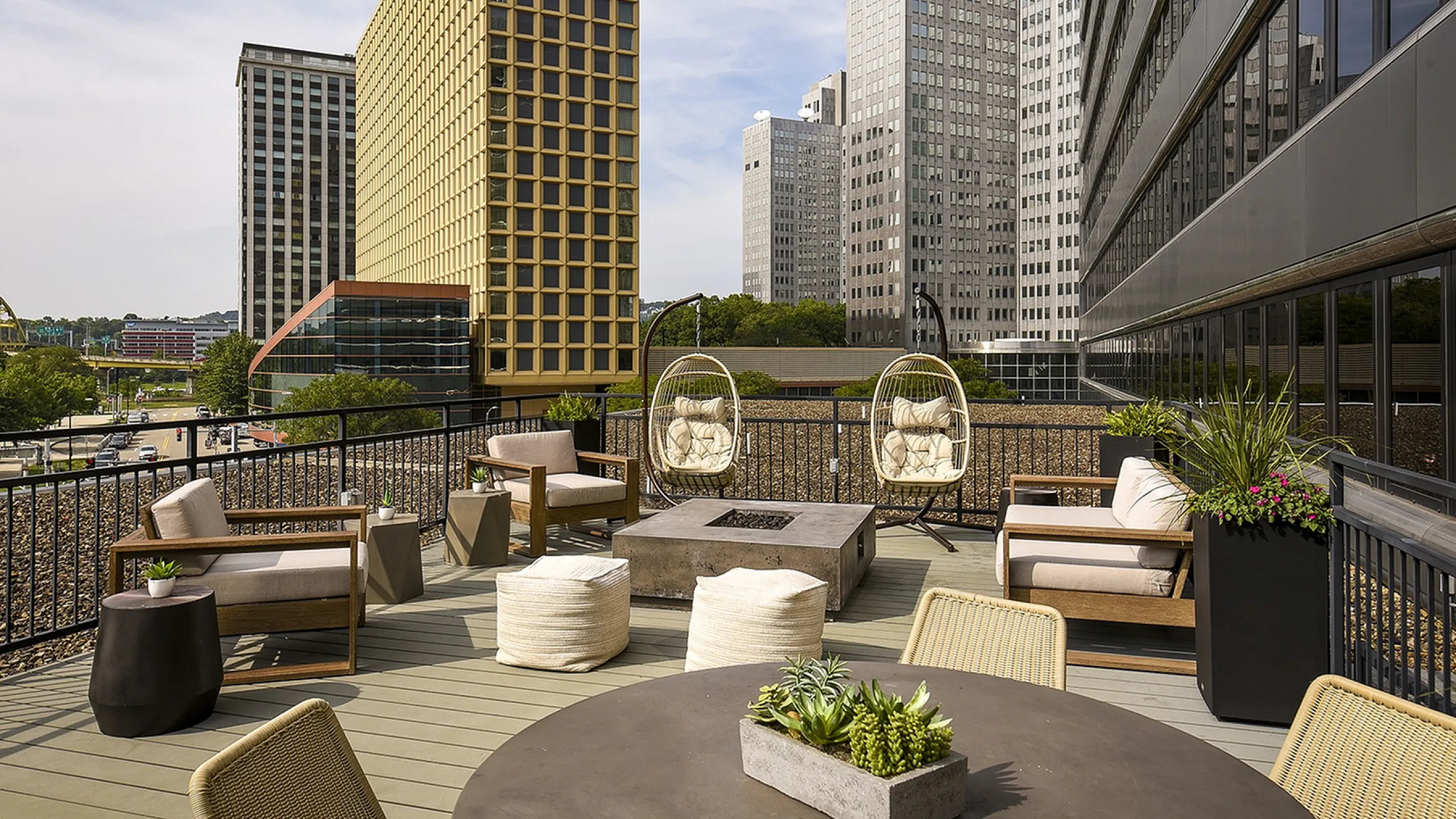 Luxurious urban rooftop terrace with modern seating, stylish fire pit, and scenic city skyline views.