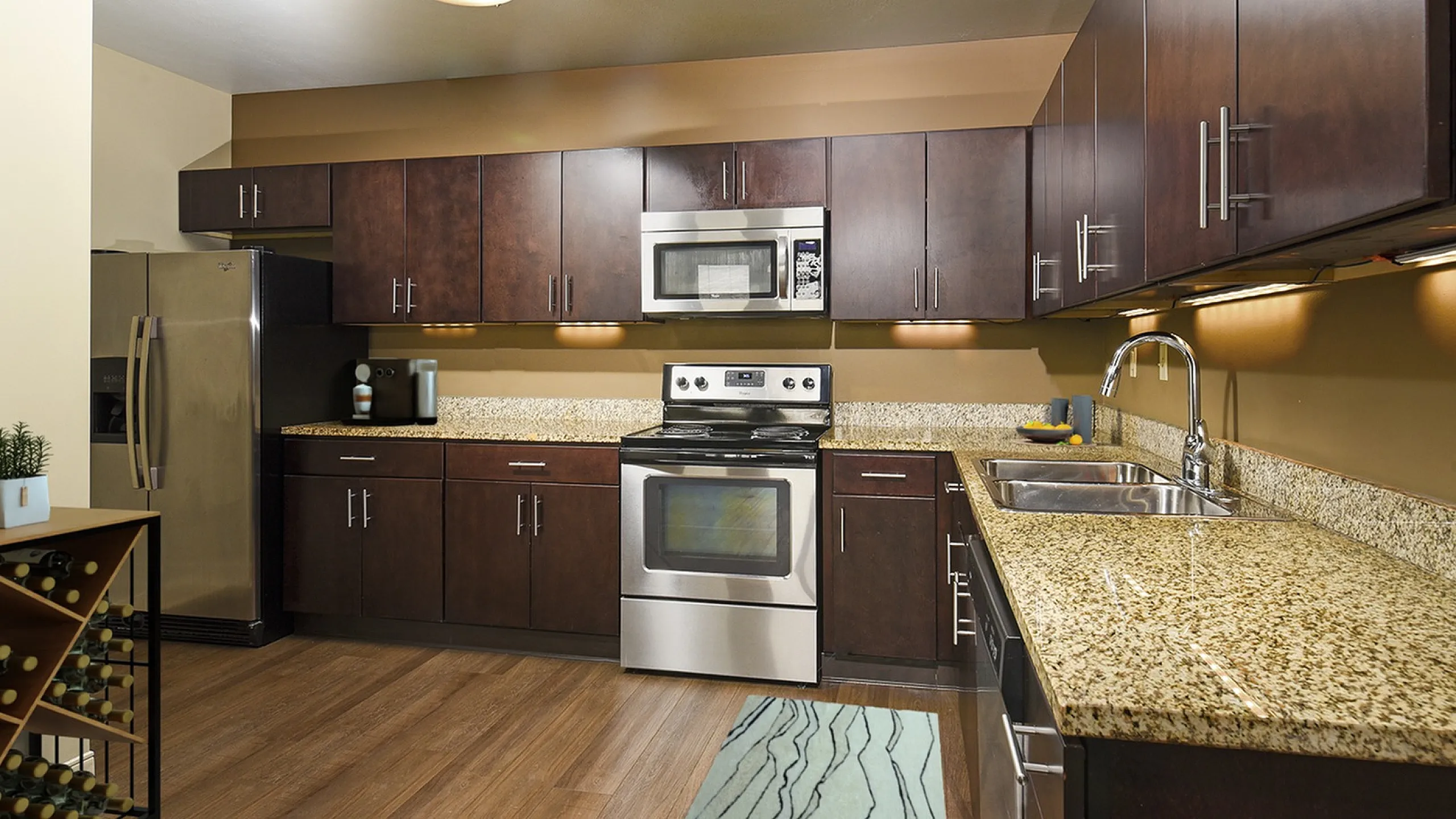 Modern kitchen with sleek dark wood cabinets, stainless steel appliances, and elegant granite countertops, perfect for culinary enthusiasts.