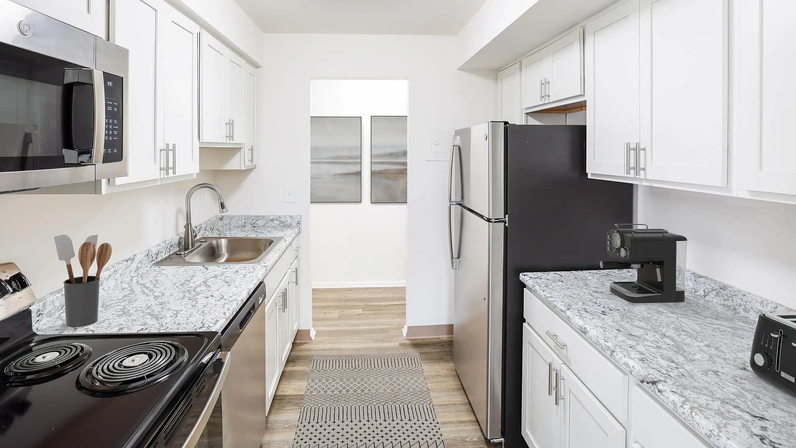 Modern kitchen with sleek stainless steel appliances, elegant white cabinetry, and stylish granite countertops.