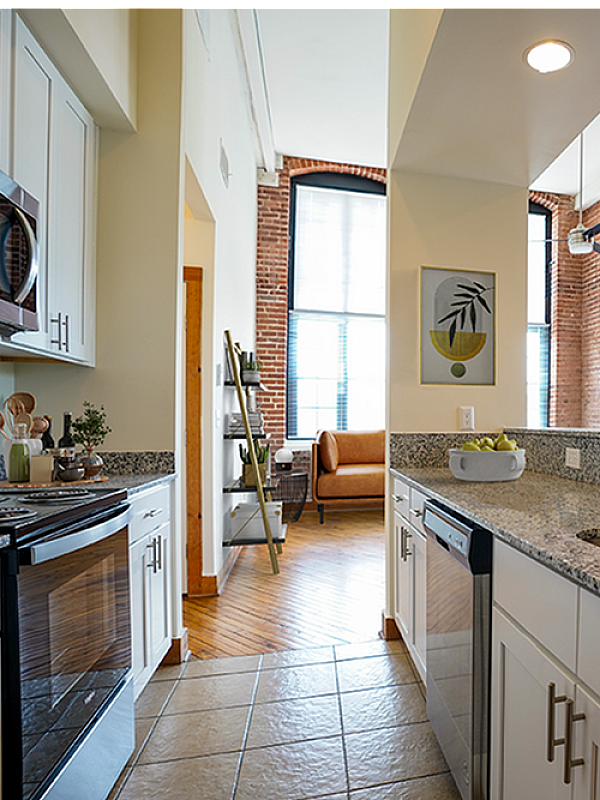 Chic urban kitchen with sleek granite countertops, stainless steel appliances, and exposed brick walls, offering a stylish and cozy atmosphere.