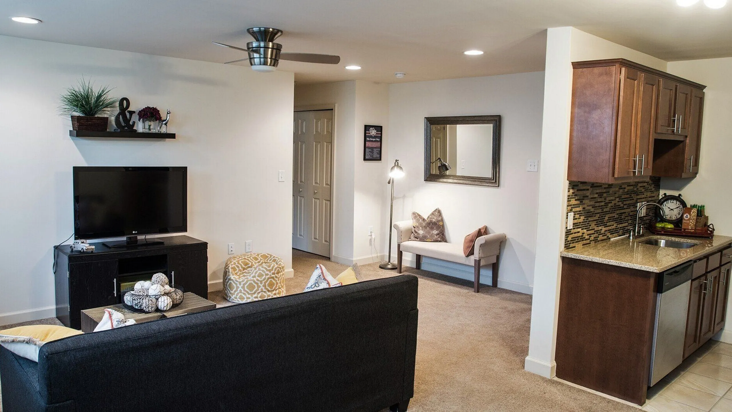 Modern apartment living room with cozy seating, stylish wall decor, open concept kitchen, and warm lighting.