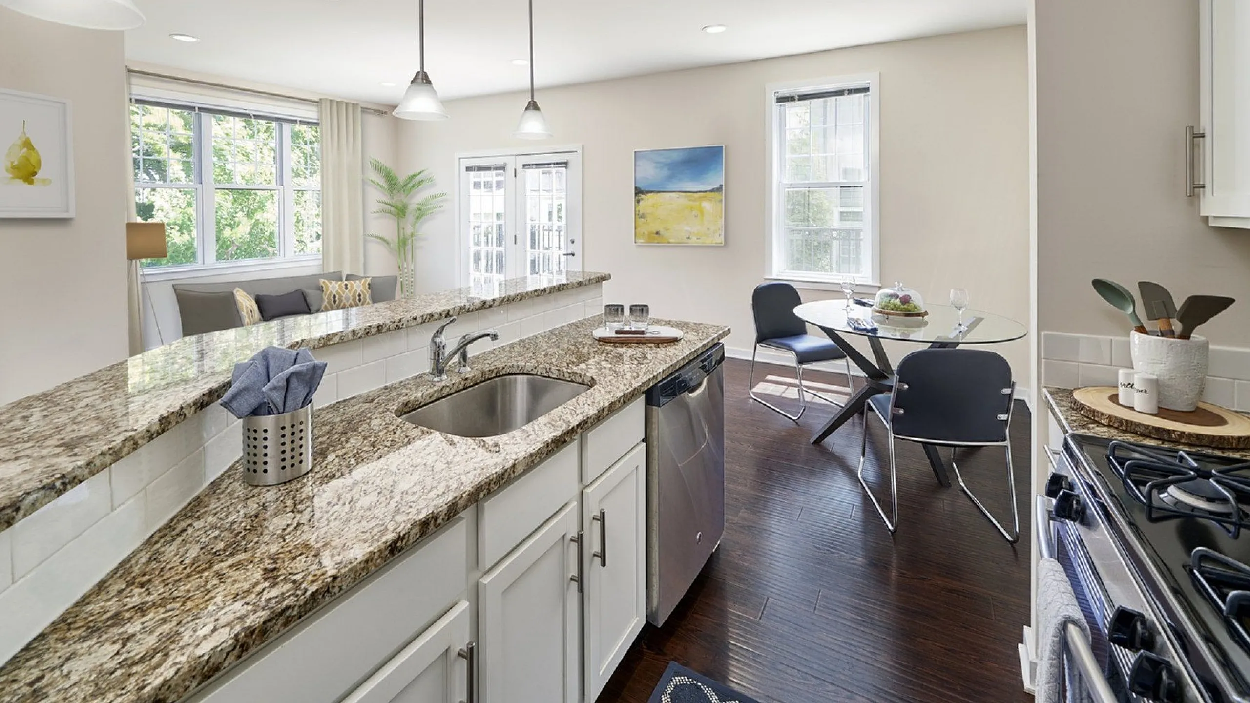 Bright, contemporary kitchen with granite countertops, open layout, and charming dining area featuring large windows and elegant lighting.