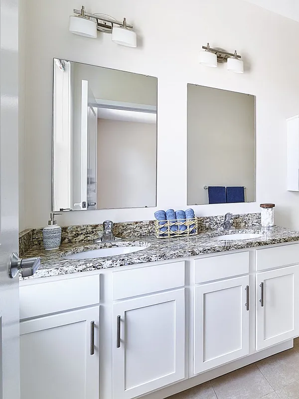 Elegant bathroom with dual sinks, granite countertops, and a spacious glass-enclosed shower.