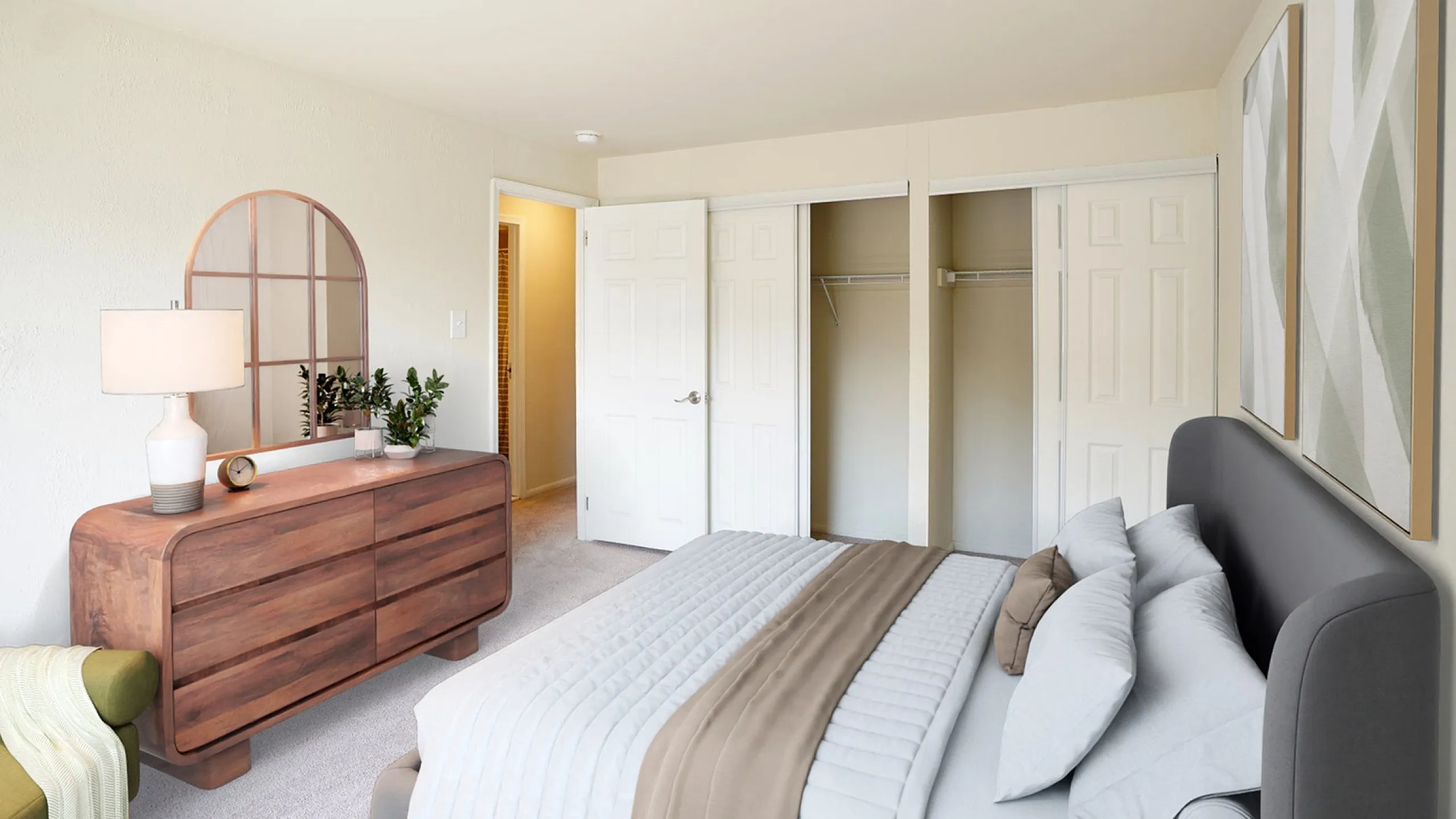 Bright and airy bedroom with elegant decor, featuring a chic wooden dresser, comfortable bedding, and ample closet space.