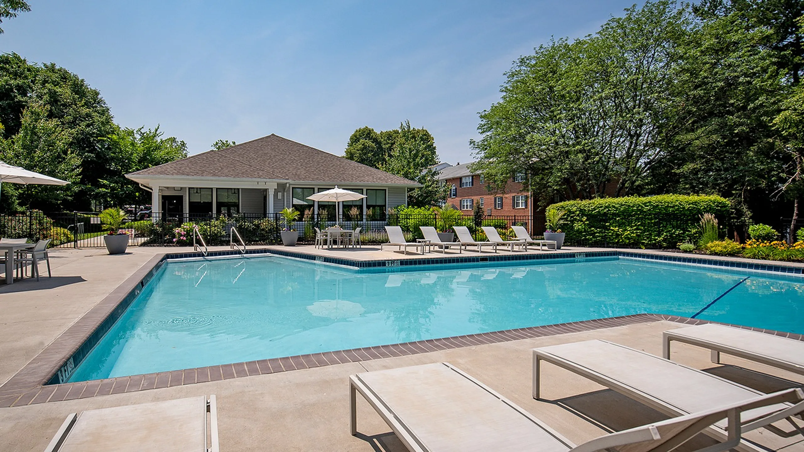 Inviting outdoor pool area with sun loungers, shaded seating, and lush green surroundings, perfect for relaxation and leisure.