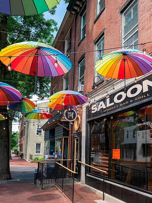 Charming street view with colorful umbrellas hanging above a vibrant whiskey bar and grill.