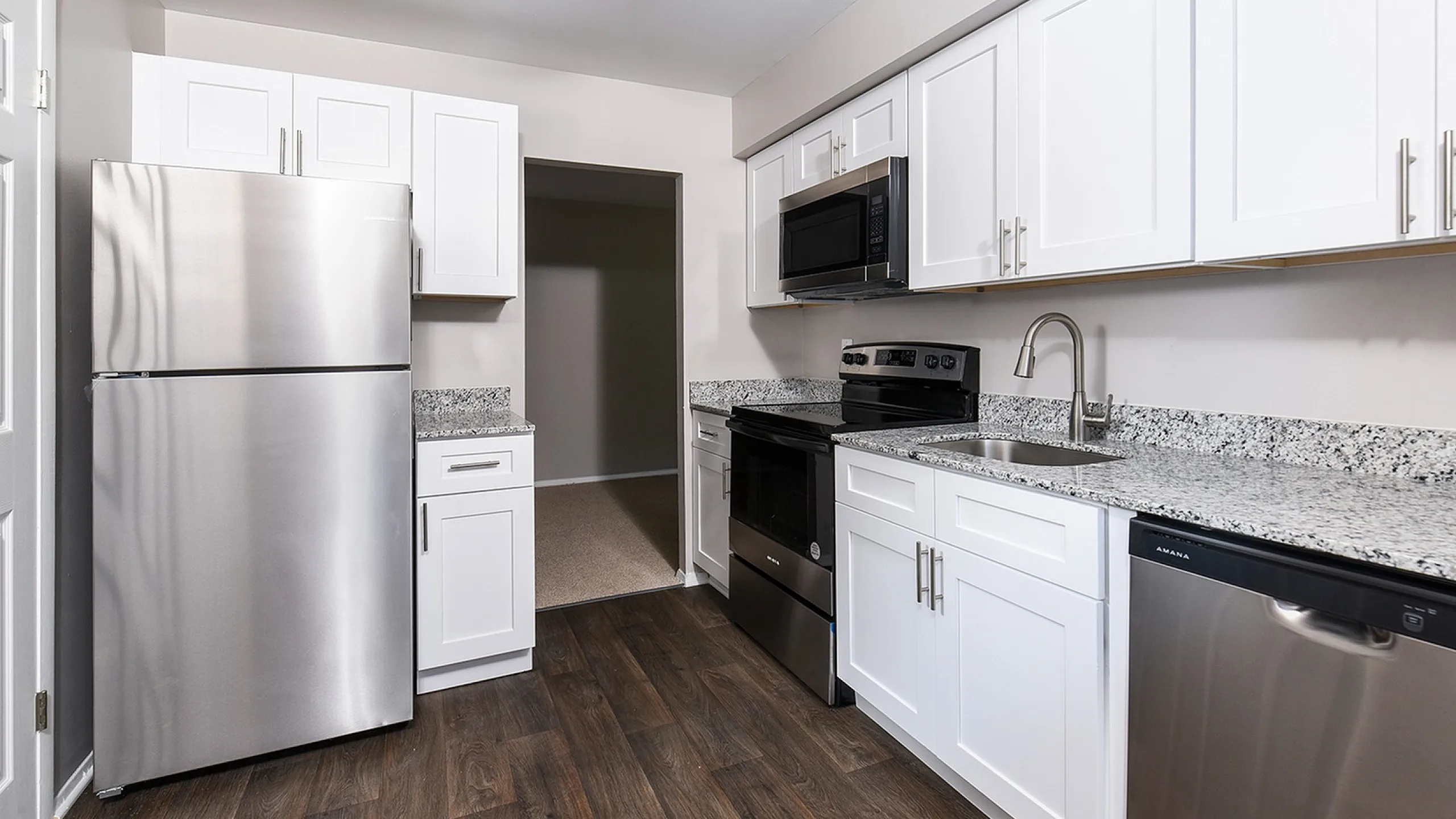 Modern kitchen with sleek stainless steel appliances, elegant white cabinetry, and granite countertops.
