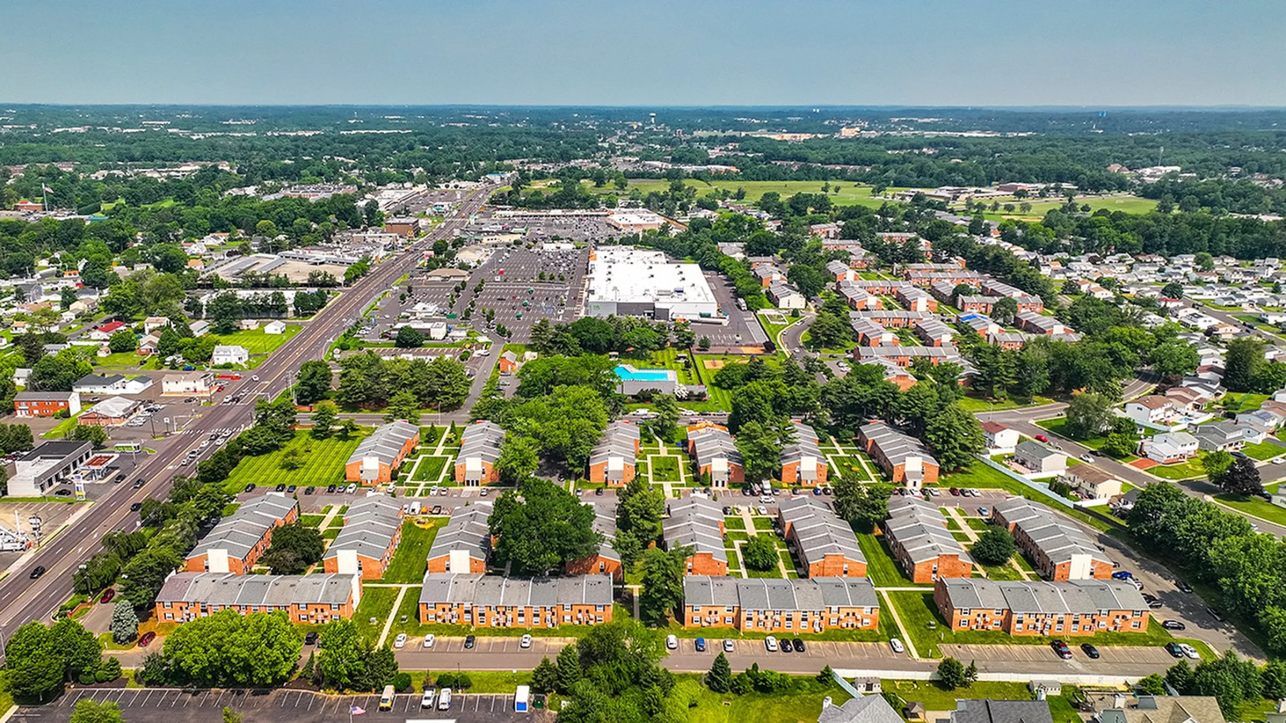 Vibrant aerial view of a well-planned apartment community surrounded by lush green spaces and nearby amenities.