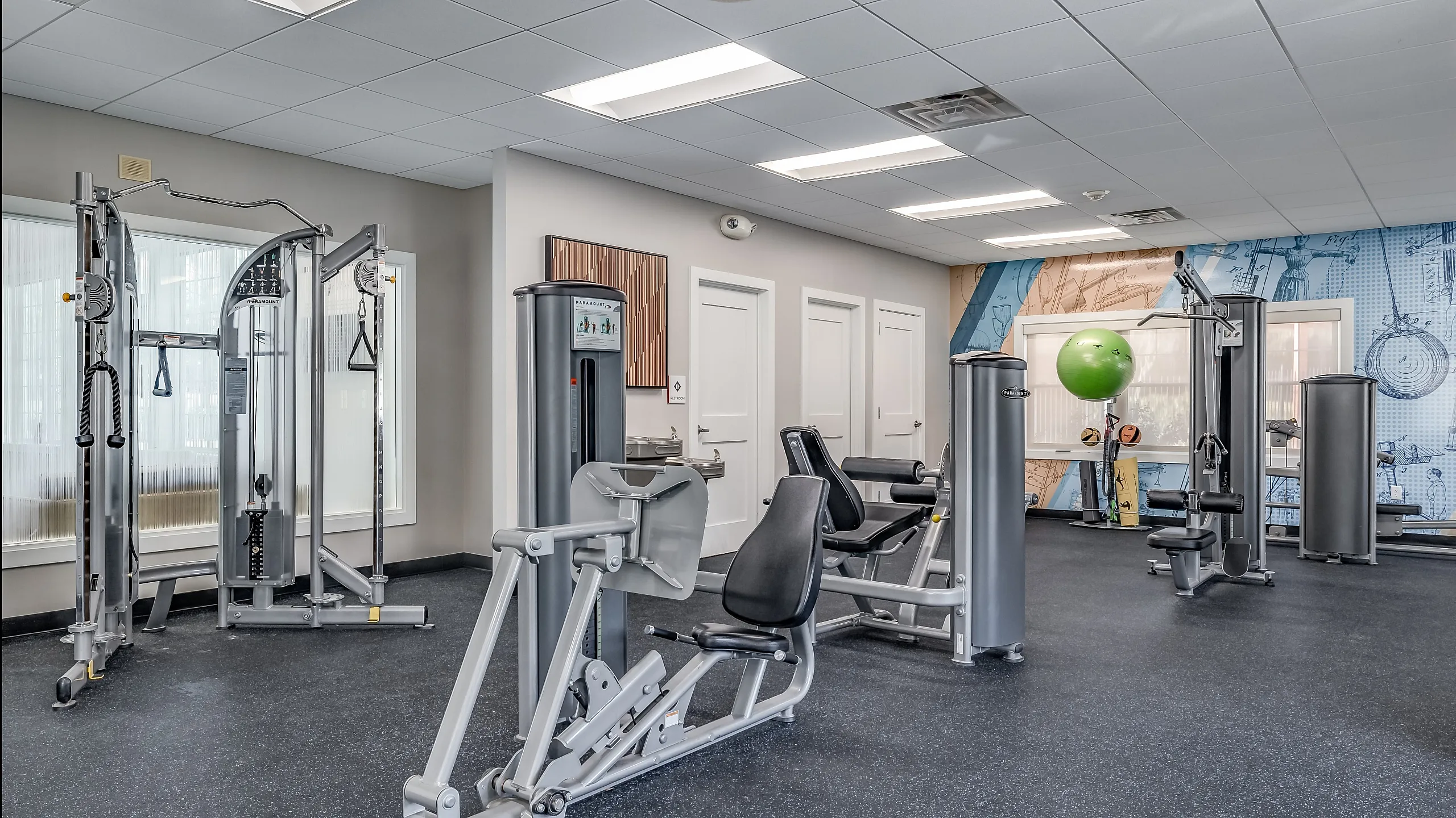 Modern fitness center featuring state-of-the-art exercise equipment, vibrant wall art, and ample natural light.