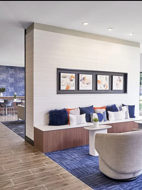 Modern apartment lounge with cozy seating, vibrant blue accents, and large windows for natural light.