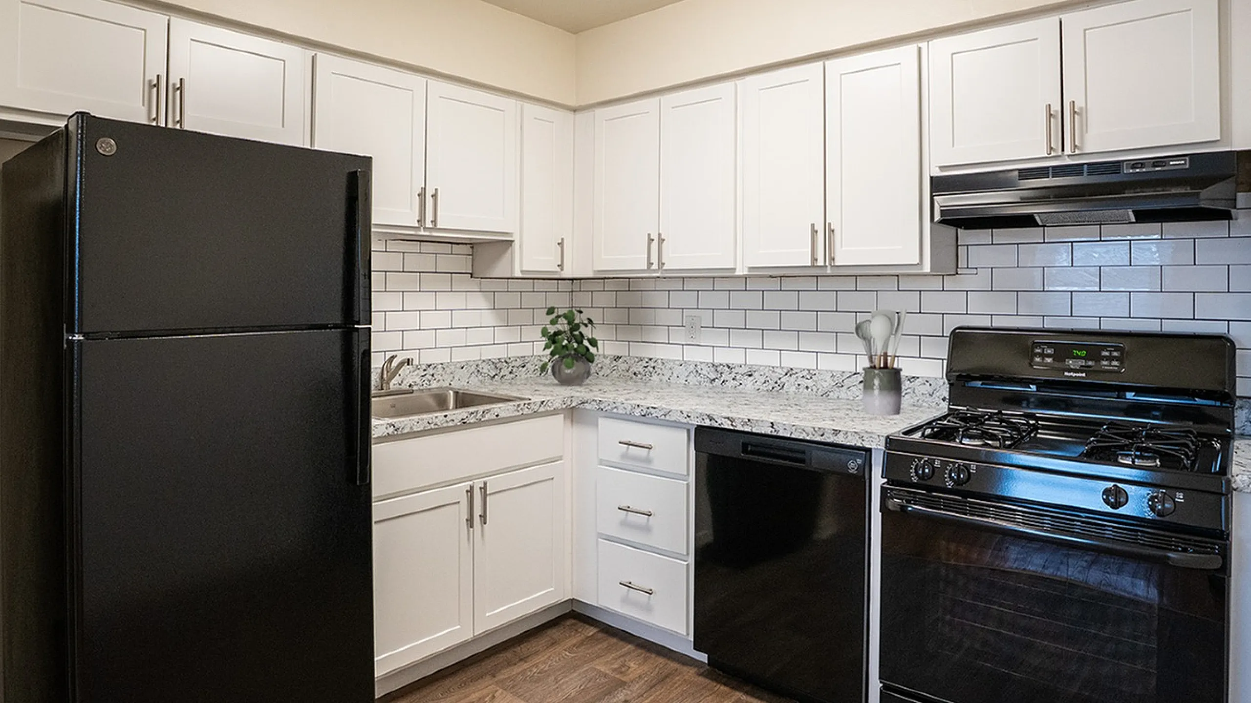 Modern kitchen with sleek black appliances, elegant white cabinets, and stylish subway tile backsplash.