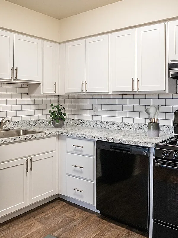 Modern kitchen with sleek black appliances, white cabinetry, and stylish subway tile backsplash offering a cozy and functional space.