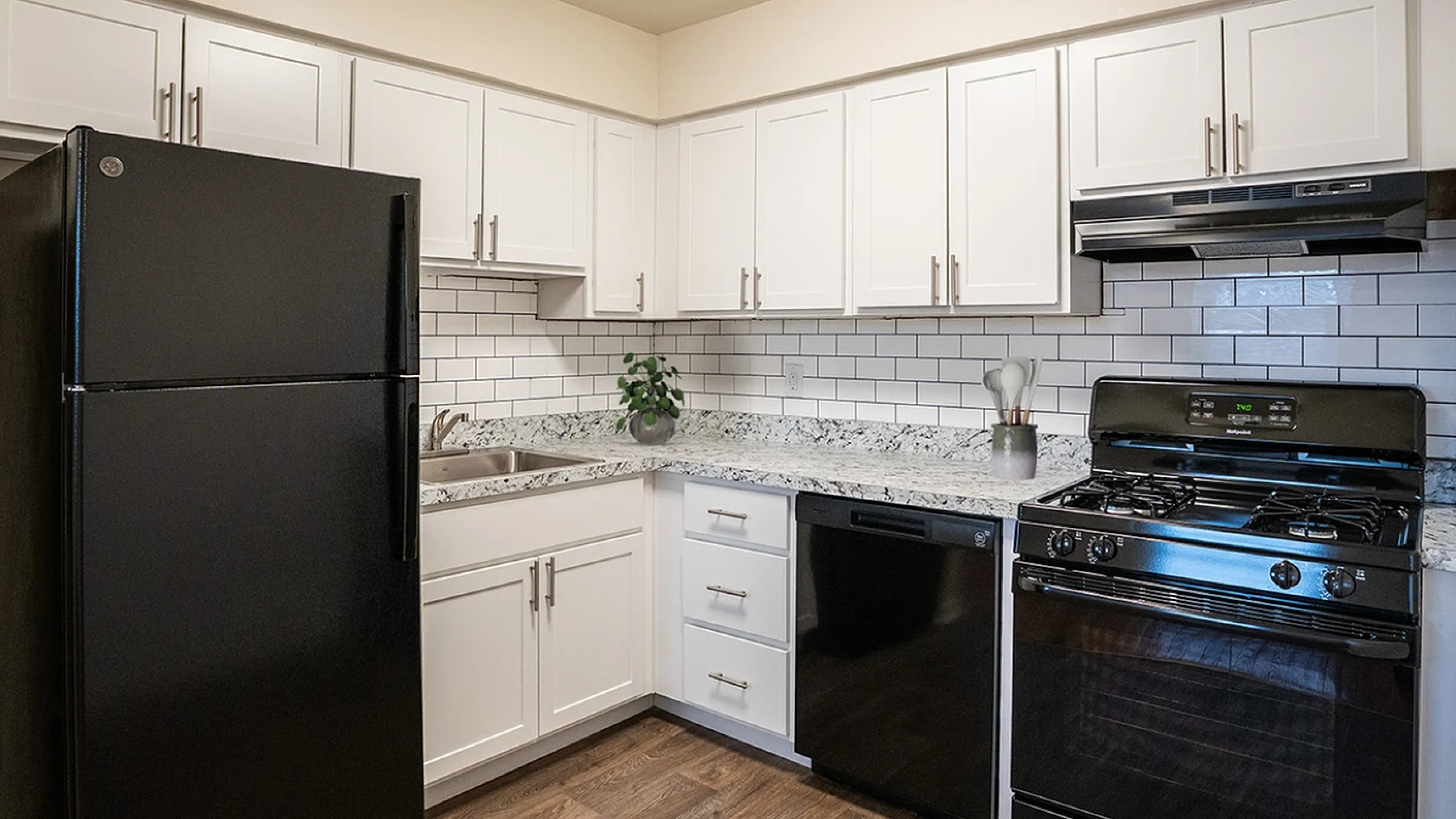 Modern kitchen with sleek black appliances, elegant granite countertops, and white subway tile backsplash.