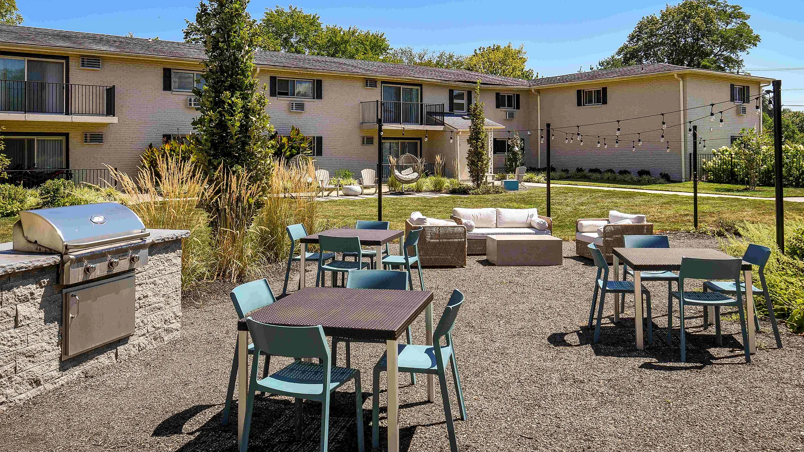 Charming outdoor space with modern grill, cozy patio furniture, and vibrant garden backdrop for entertaining.