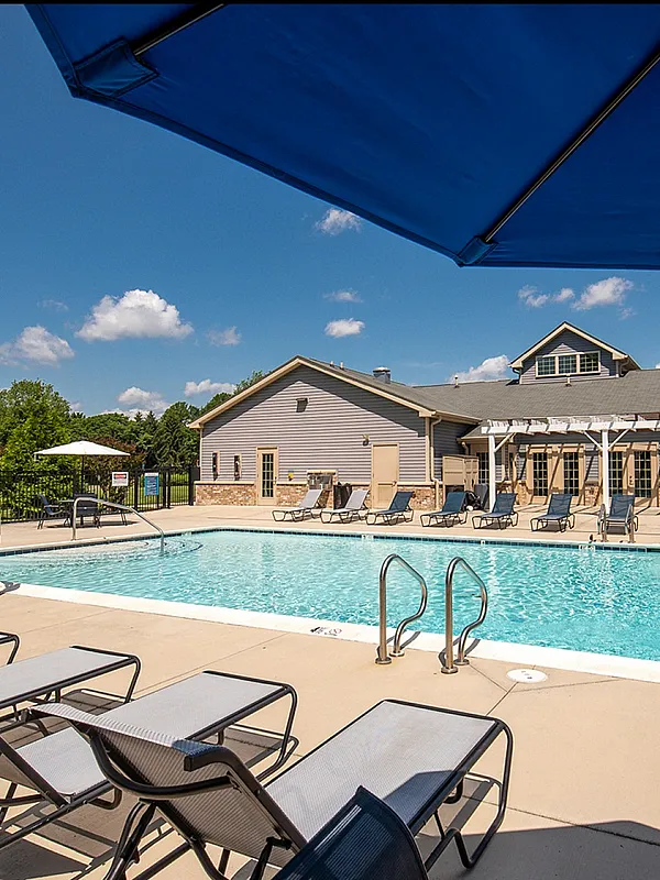Inviting swimming pool area with sun loungers and umbrellas under a clear blue sky, perfect for relaxation.