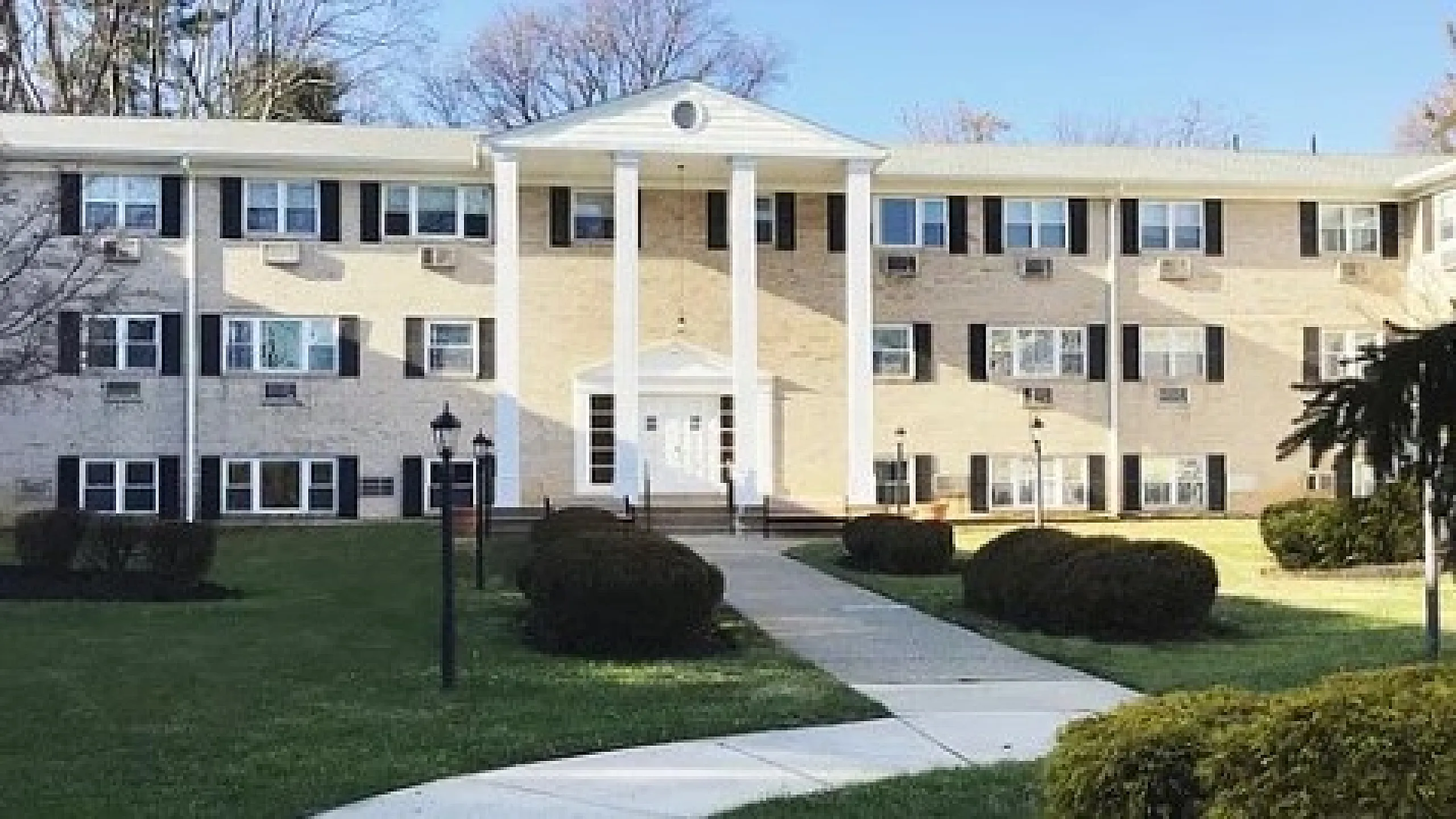 Charming apartment building with classic architecture, featuring white columns and well-maintained landscaping.