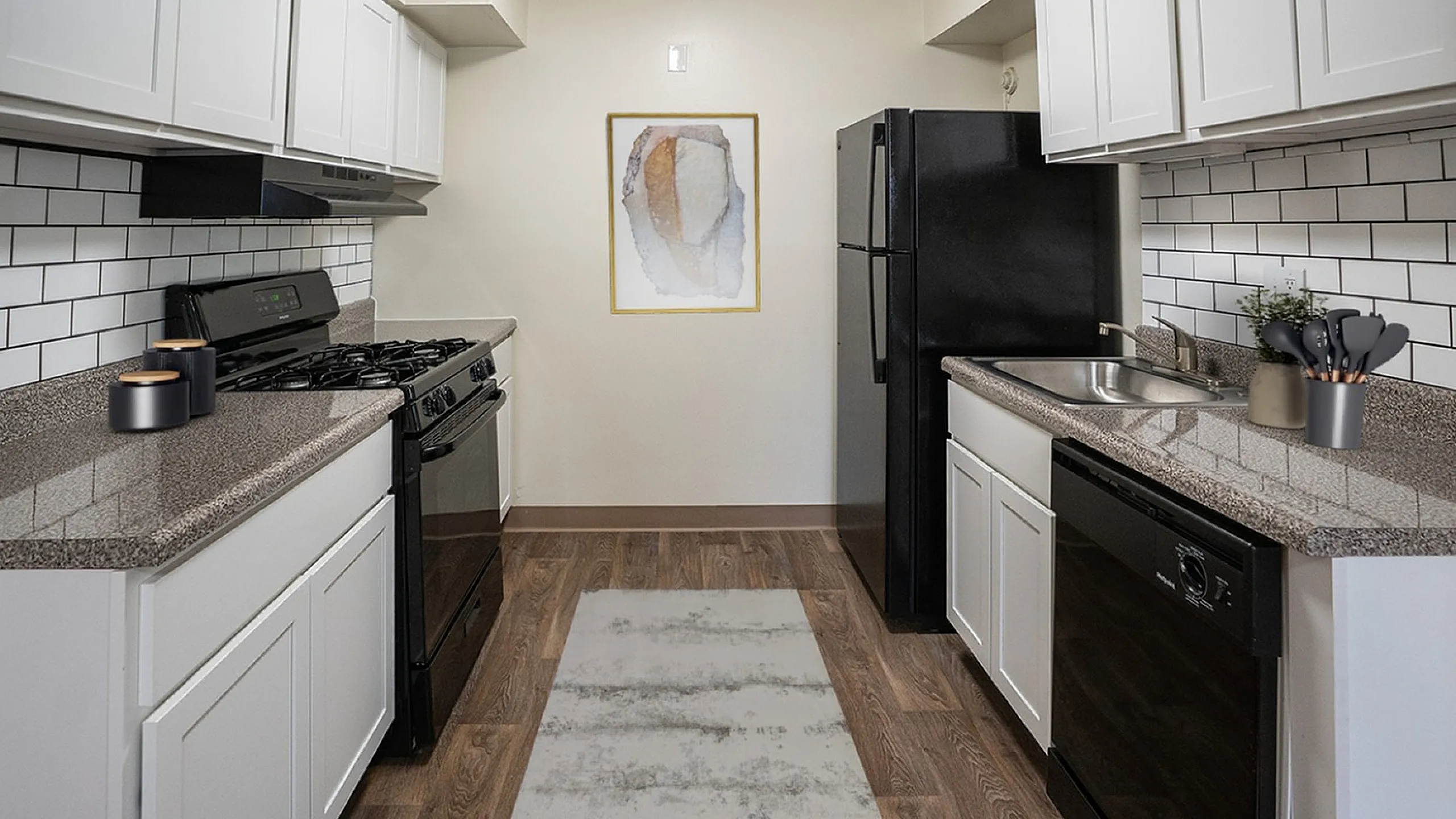 Modern kitchen with sleek black appliances, elegant granite countertops, white cabinetry, and stylish subway tile backsplash, perfect for culinary creativity.