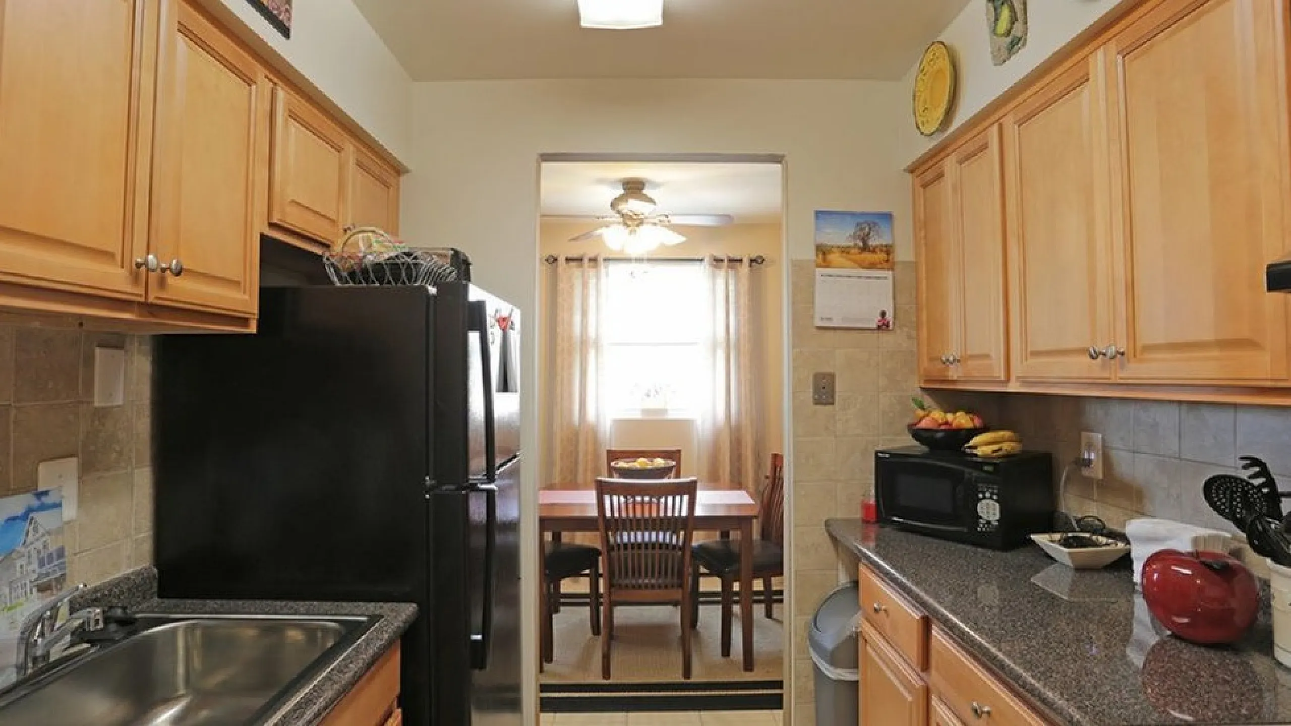 Charming kitchen with warm wooden cabinets and sleek countertops, leading to a bright dining area with natural light.