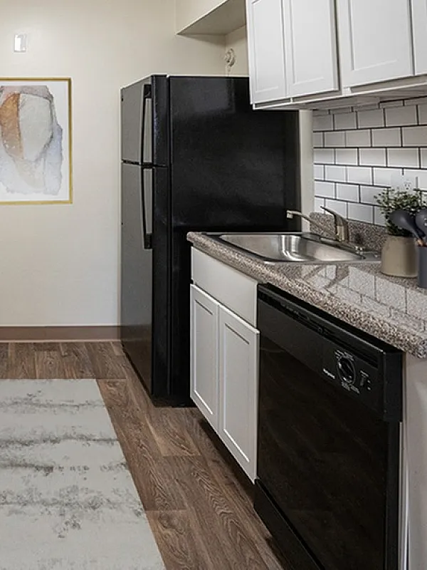 Modern kitchen with sleek countertops, white cabinetry, and stylish appliances, accented by a decorative wall art piece.