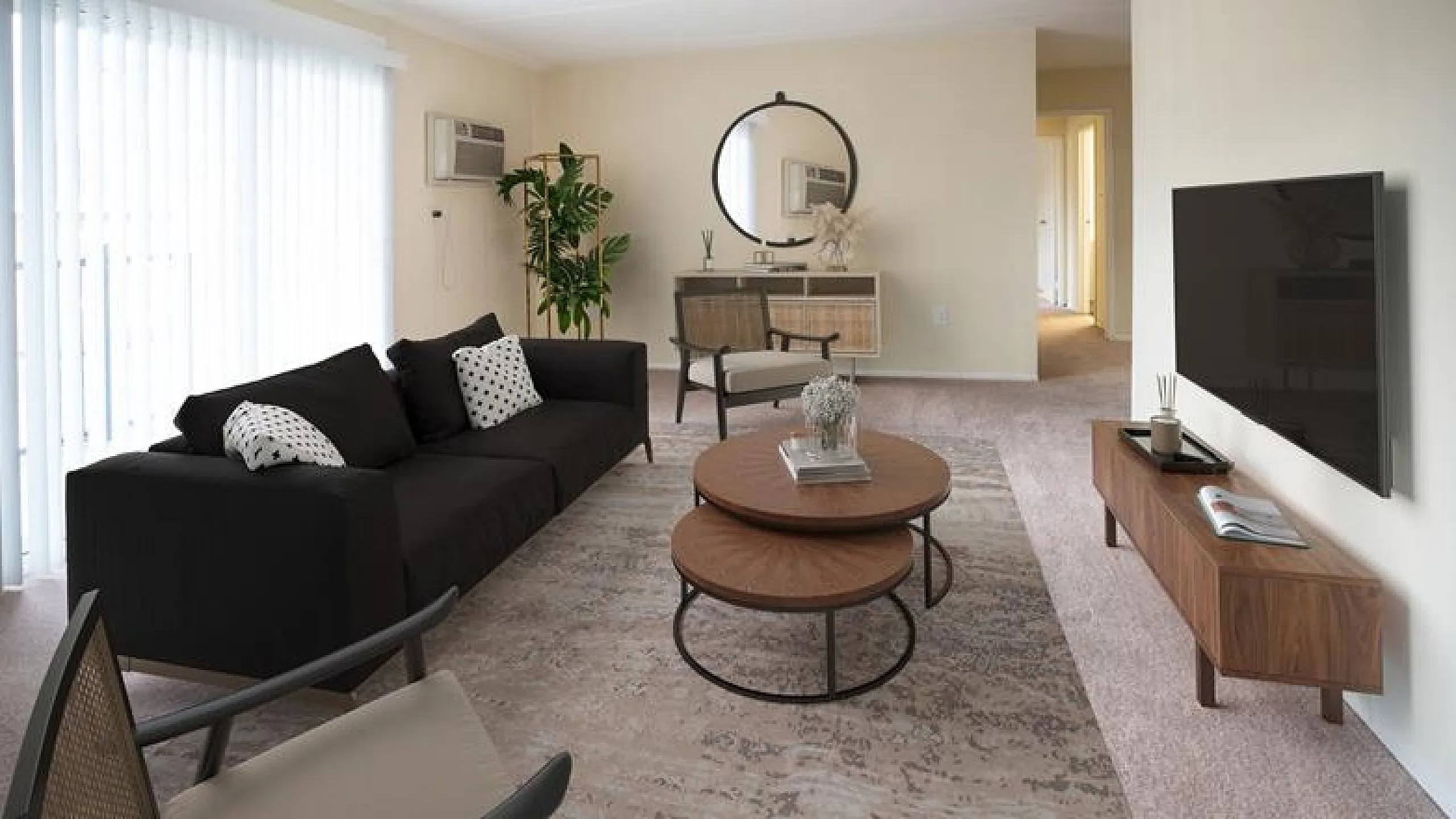 Elegant living room with modern decor, featuring a chic black sofa, stylish round coffee tables, and a flat-screen TV, perfect for relaxation and entertainment.