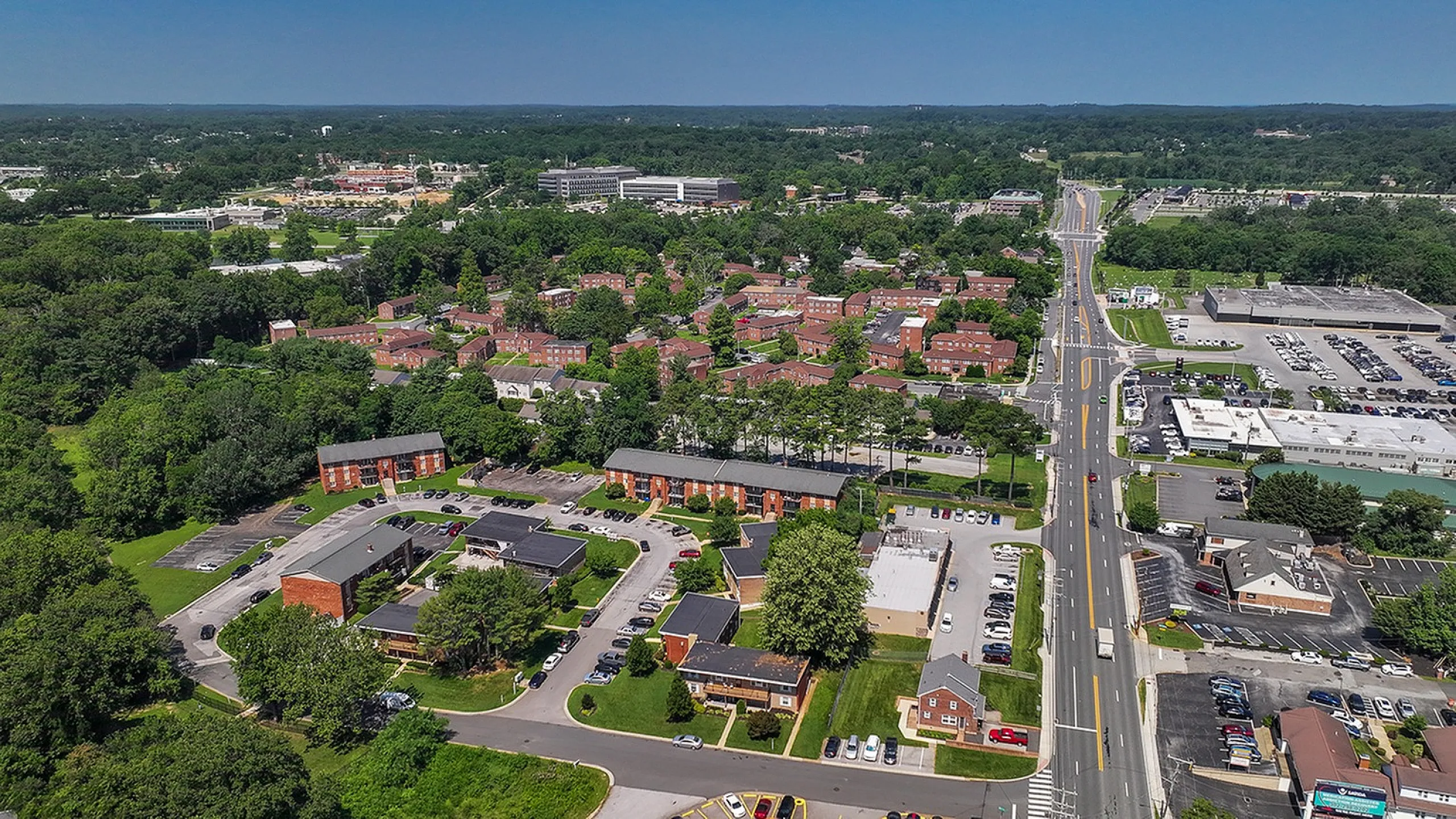 Scenic aerial view showcasing a vibrant apartment community surrounded by lush greenery, highlighting accessibility and convenience with nearby roads and facilities.