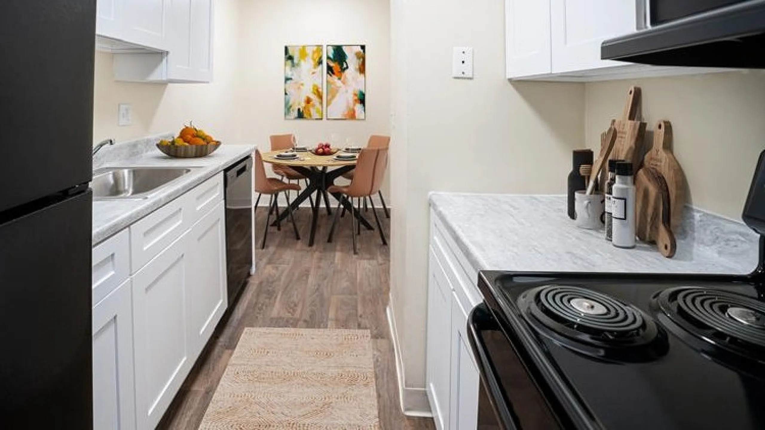 Sleek kitchen design with modern appliances, elegant beige cabinetry, and a cozy dining area with vibrant artwork, ideal for stylish living.