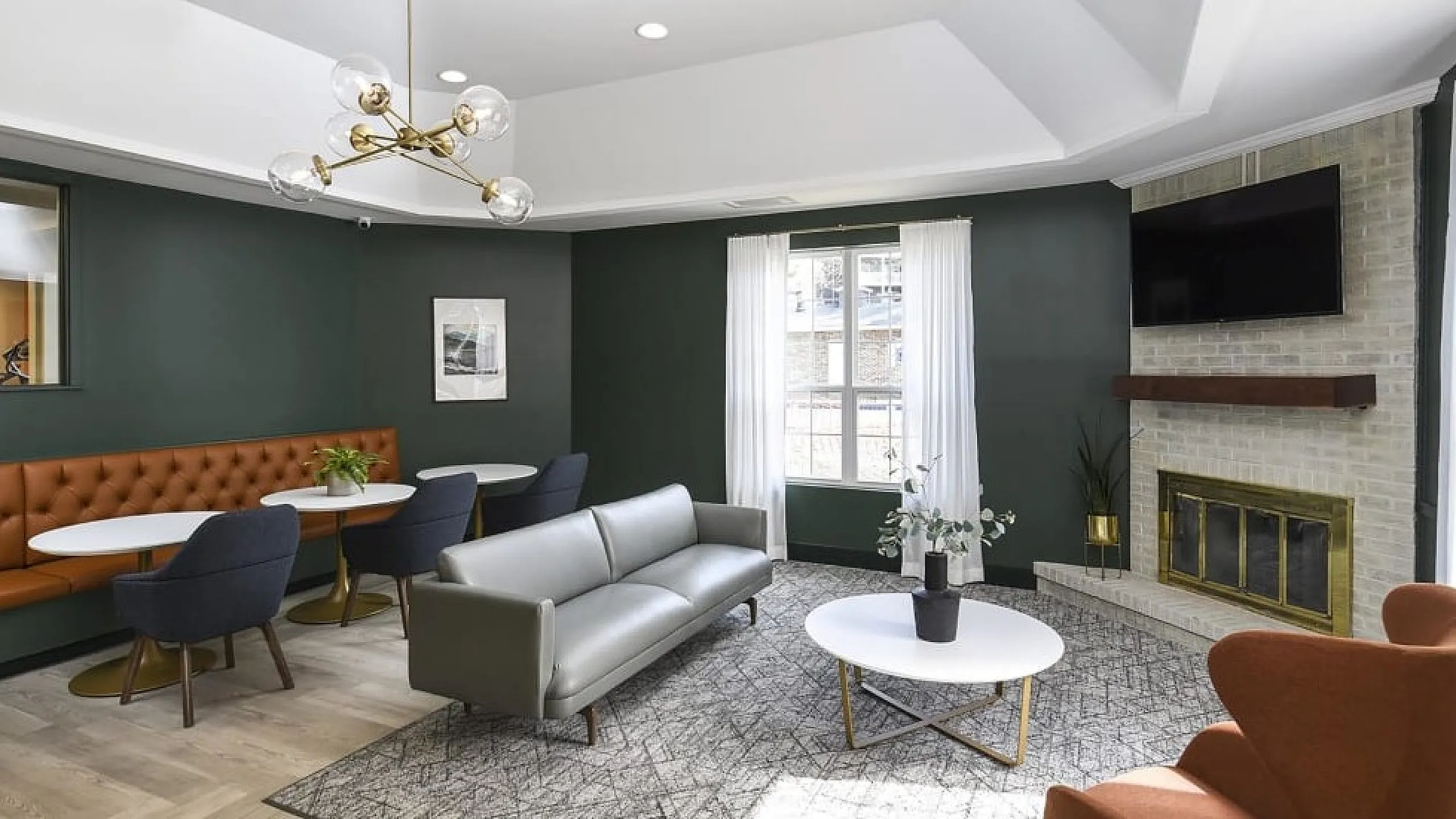 Elegant living room featuring modern furnishings, a cozy fireplace, and ample natural light. Stylish seating area with chic chairs and coffee tables.