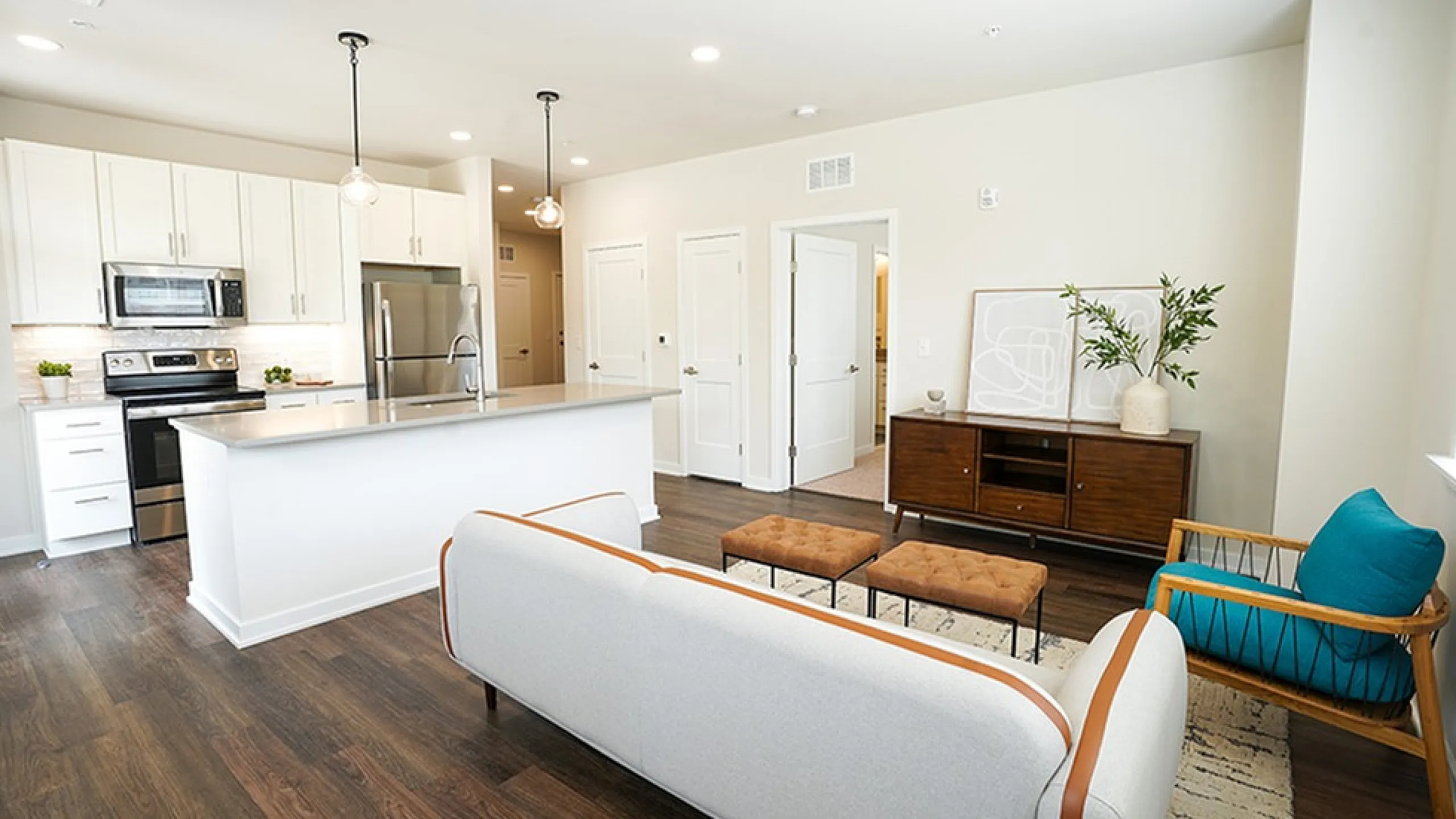 Contemporary open-concept living room and kitchen with sleek white cabinetry, modern appliances, and elegant decor.