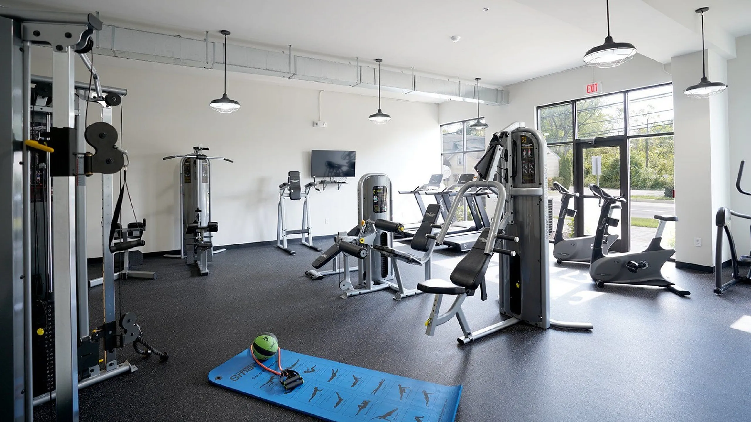 Modern fitness center featuring state-of-the-art exercise equipment, bright natural lighting, and spacious workout area for a premium lifestyle experience.