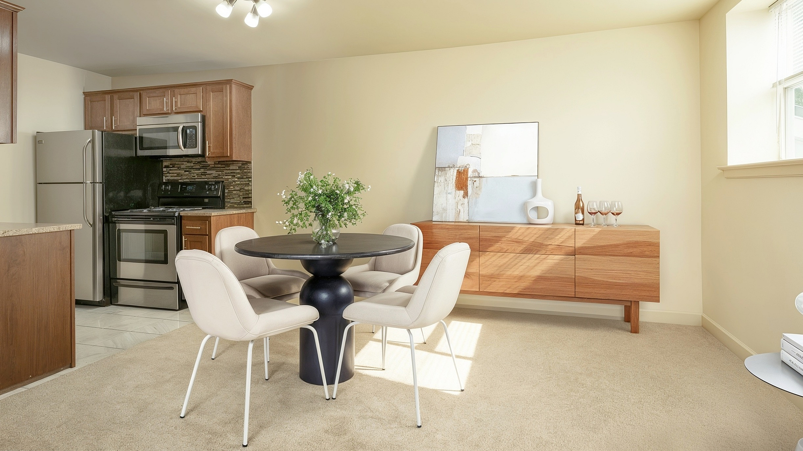 Inviting dining area with elegant table, modern chairs, and a stylish kitchen featuring stainless steel appliances and warm wood cabinetry.