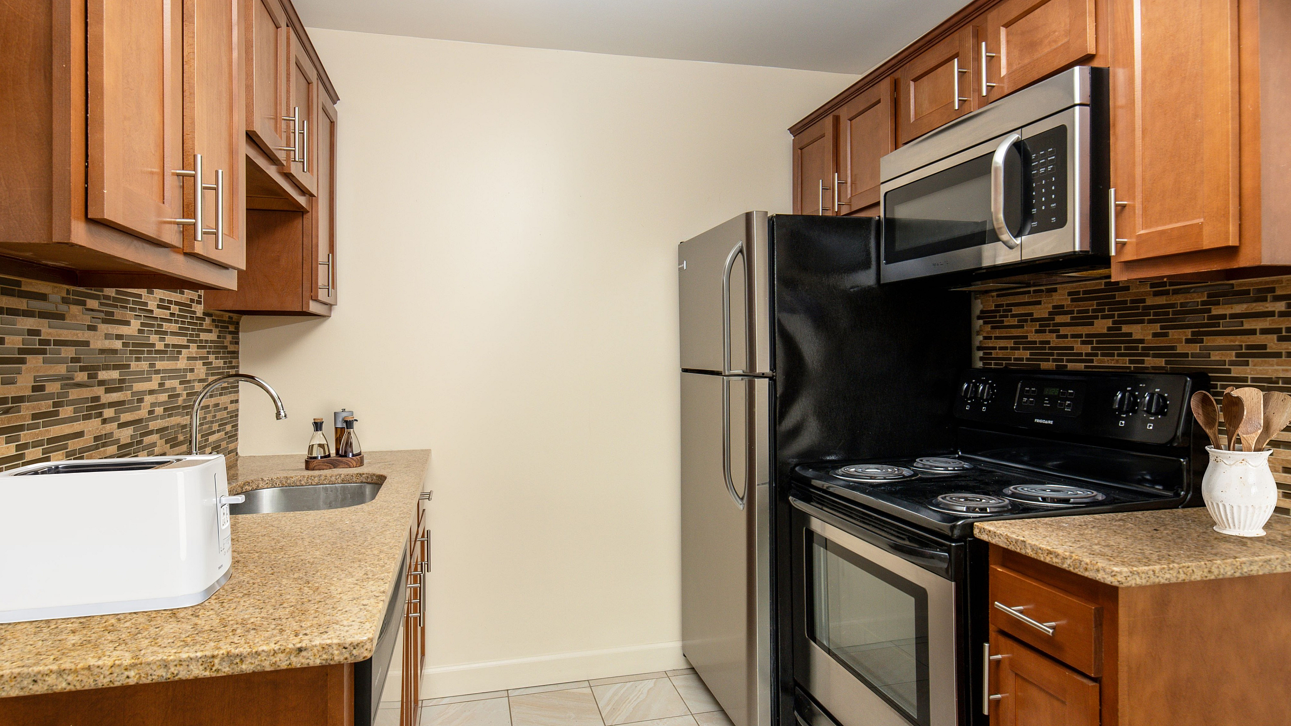 Modern kitchen with sleek stainless steel appliances, elegant wooden cabinets, and a stylish tile backsplash.