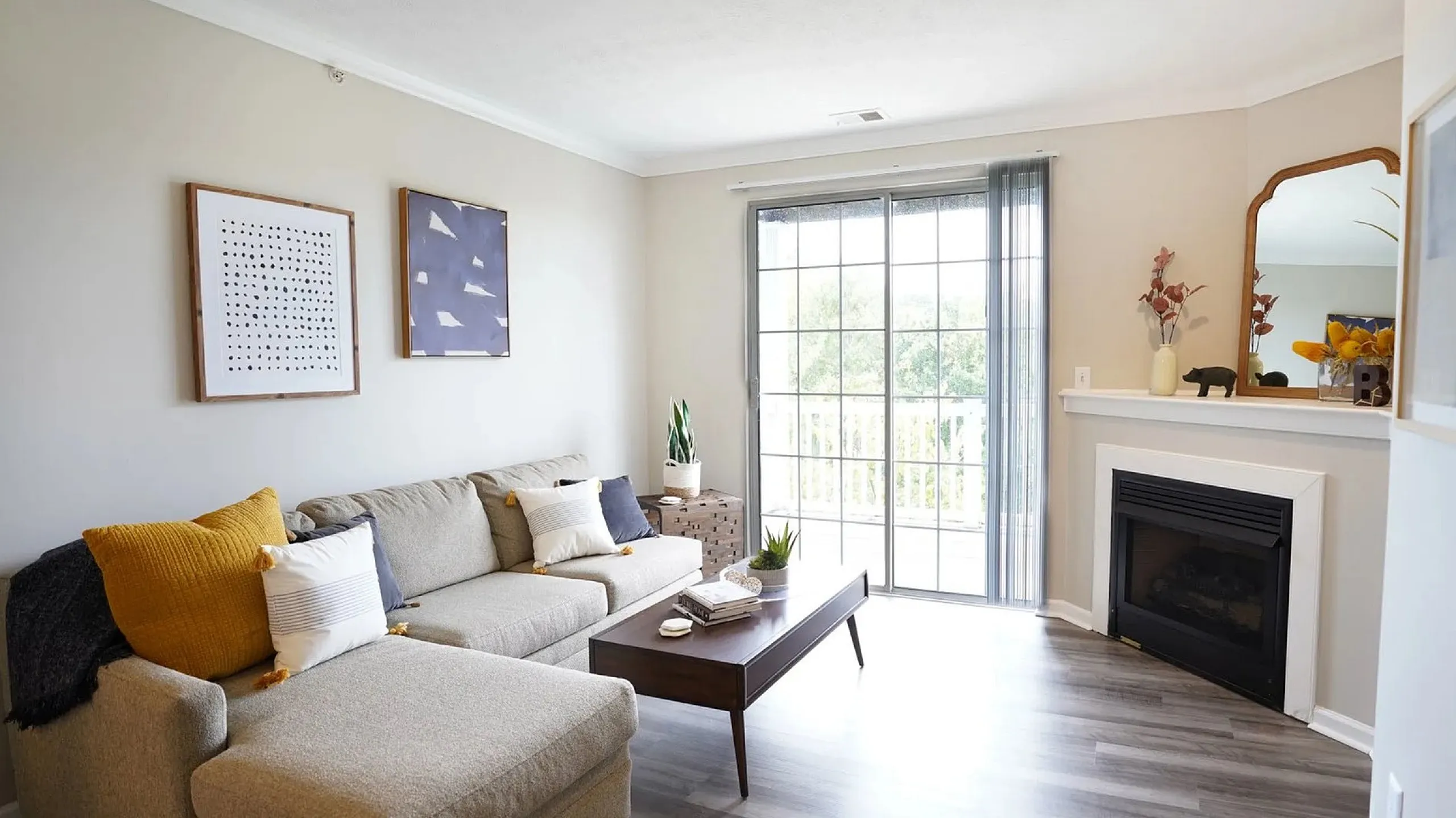Bright and inviting living room featuring a cozy sectional sofa, stylish wall art, a sleek coffee table, and a modern fireplace, with abundant natural light from large sliding glass doors.