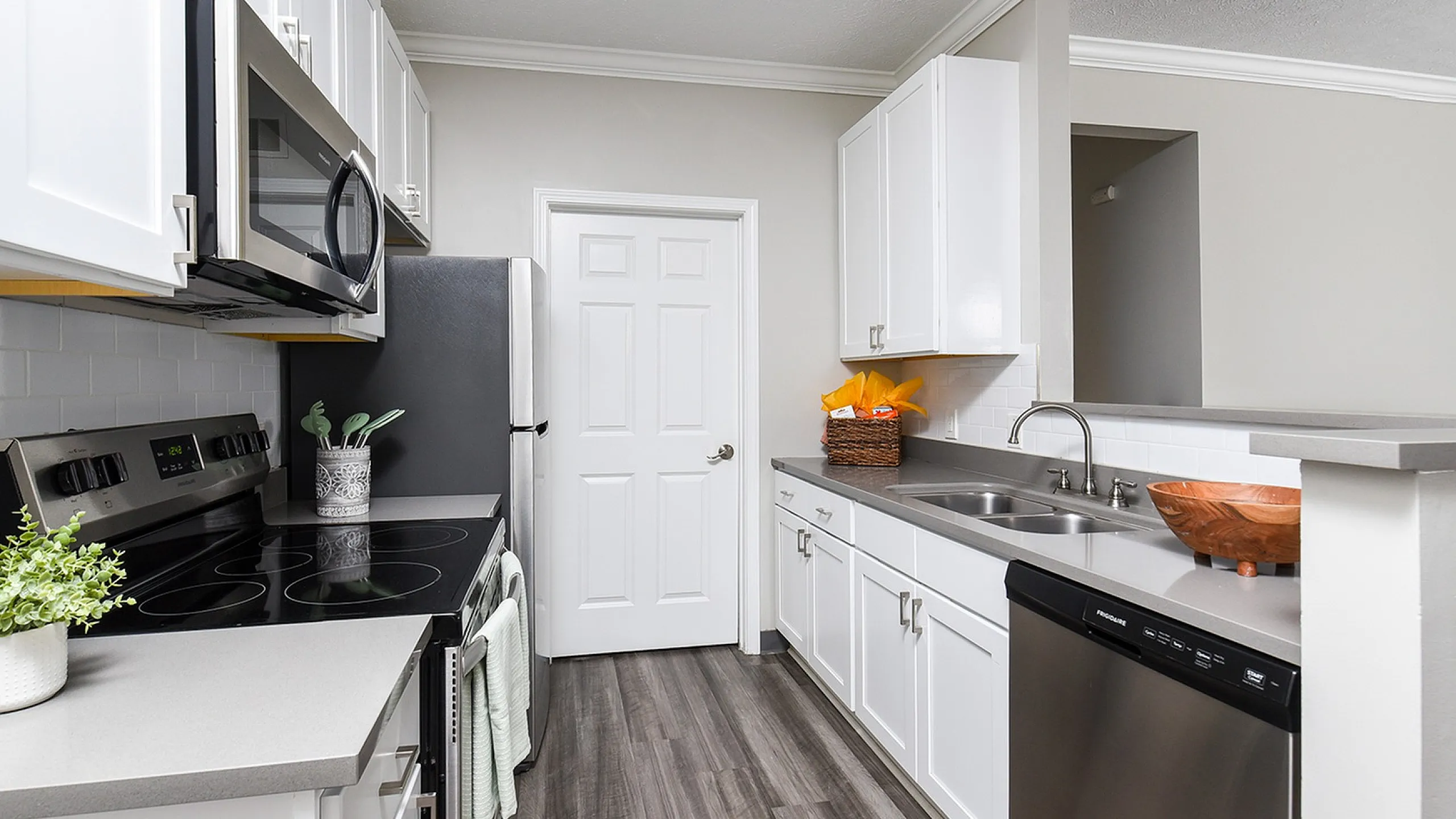 Modern kitchen with sleek stainless steel appliances, elegant white cabinetry, and stylish gray countertops, offering a clean and inviting cooking space.