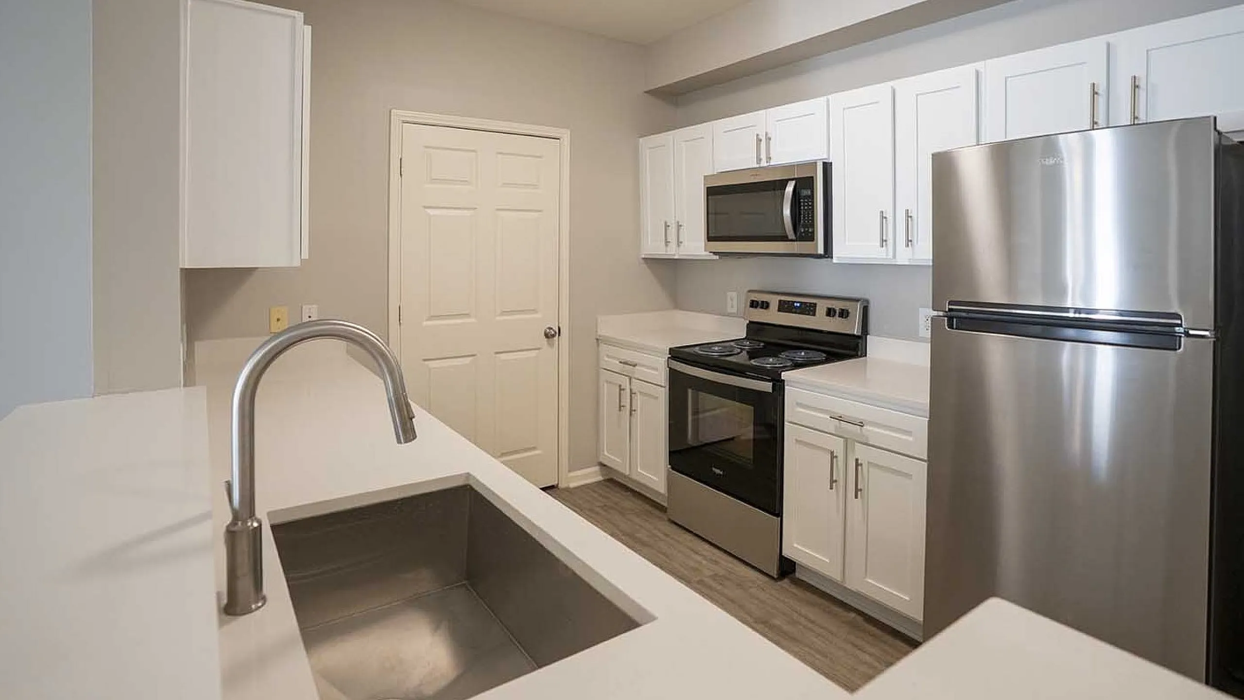 Modern kitchen featuring sleek stainless steel appliances, elegant white cabinetry, and a spacious countertop with an integrated sink.