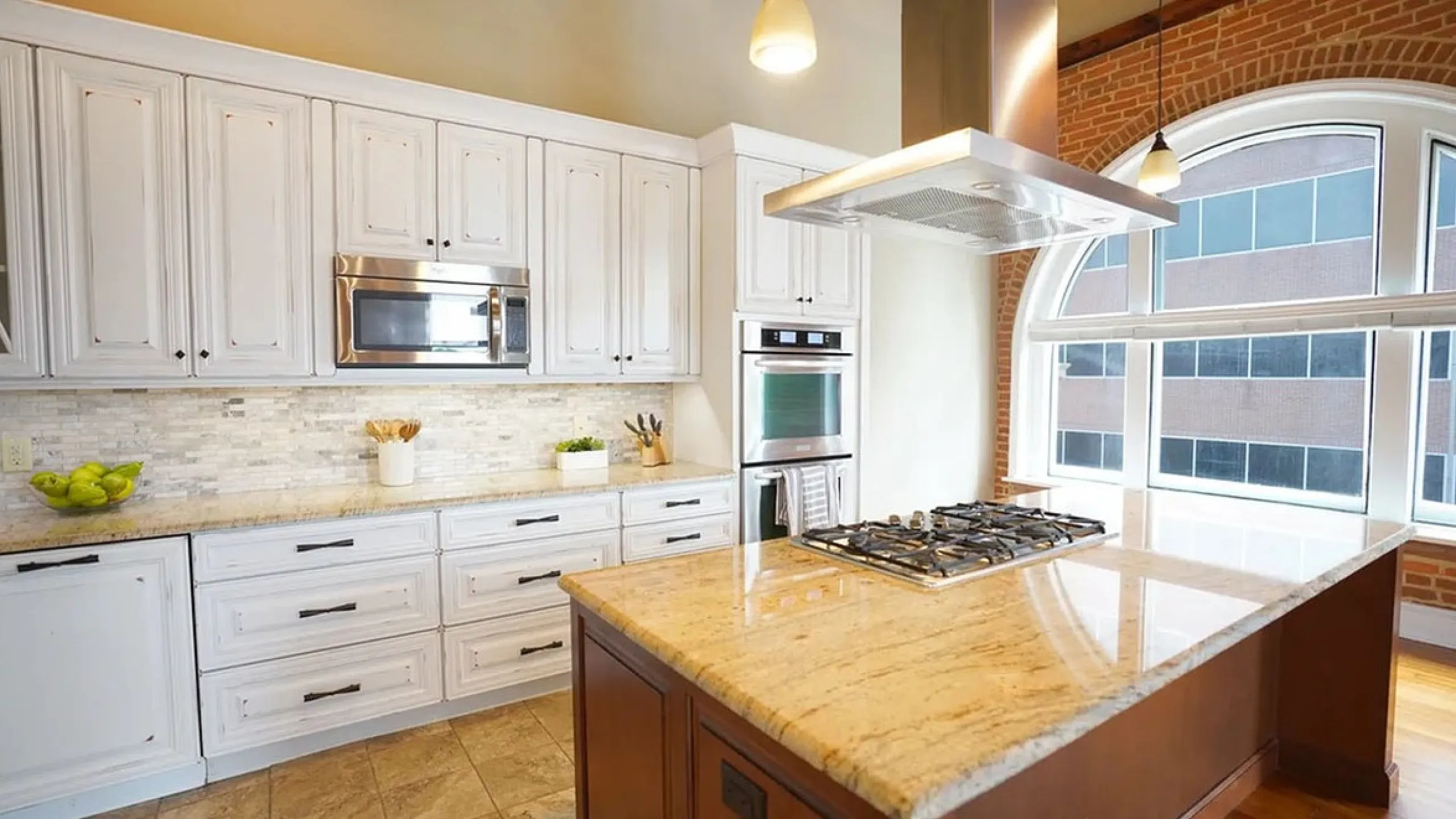 Chic modern kitchen with elegant granite countertops, sleek appliances, and large arched window for natural light.