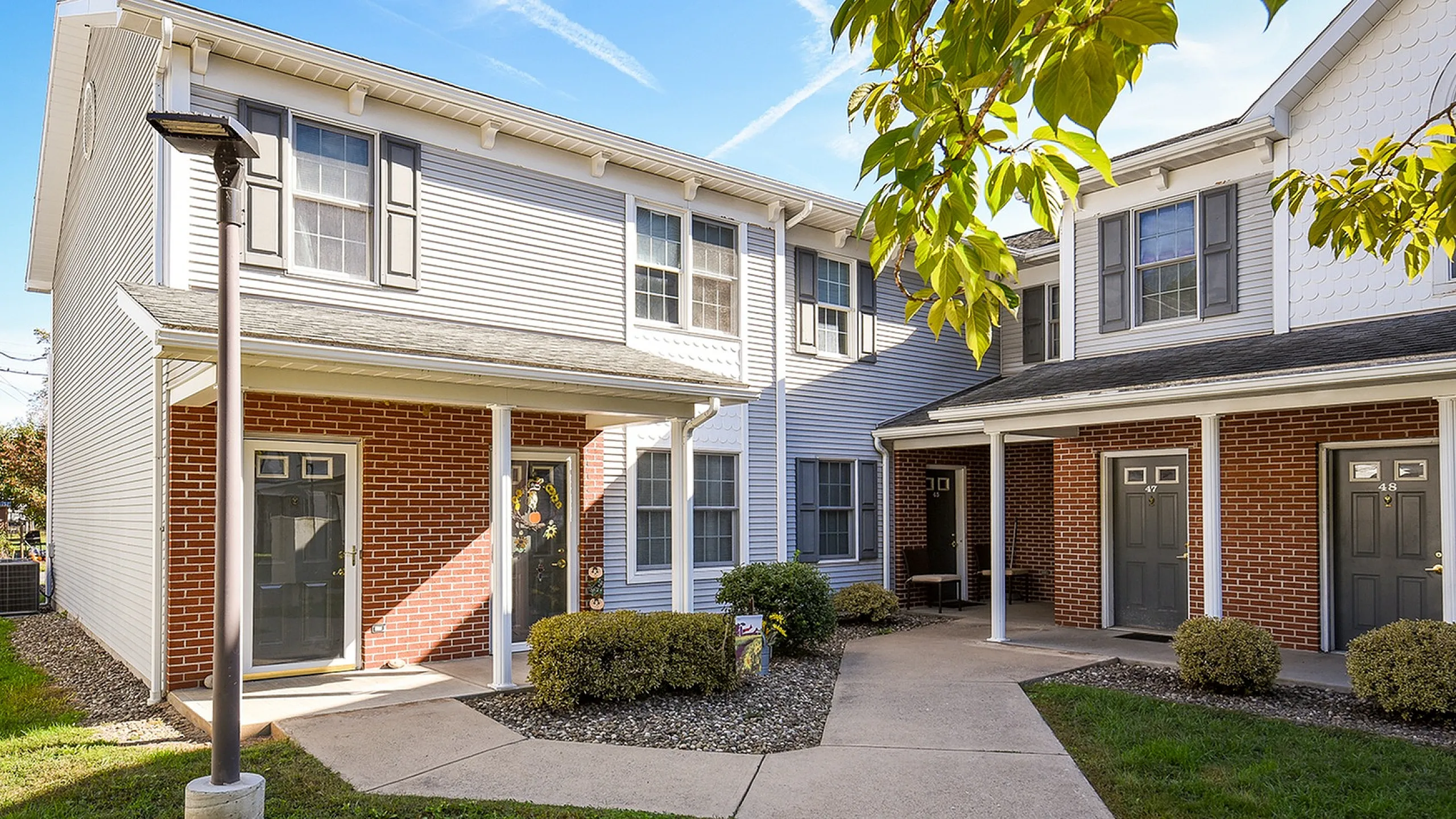 Inviting townhouse exterior featuring classic brick design, manicured landscaping, and welcoming front porches, perfect for modern living.