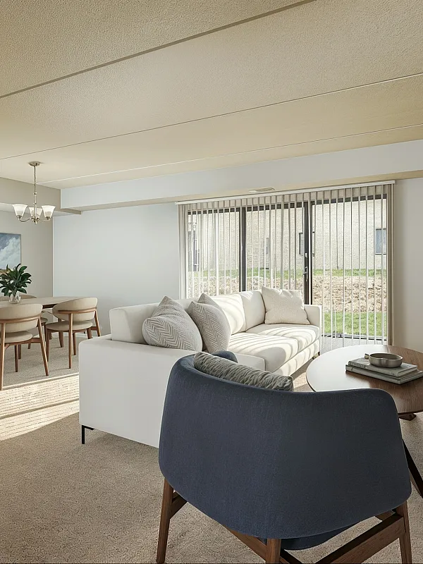 Elegant, sunlit living room with modern furniture and a cozy dining area, showcasing large windows and stylish decor.
