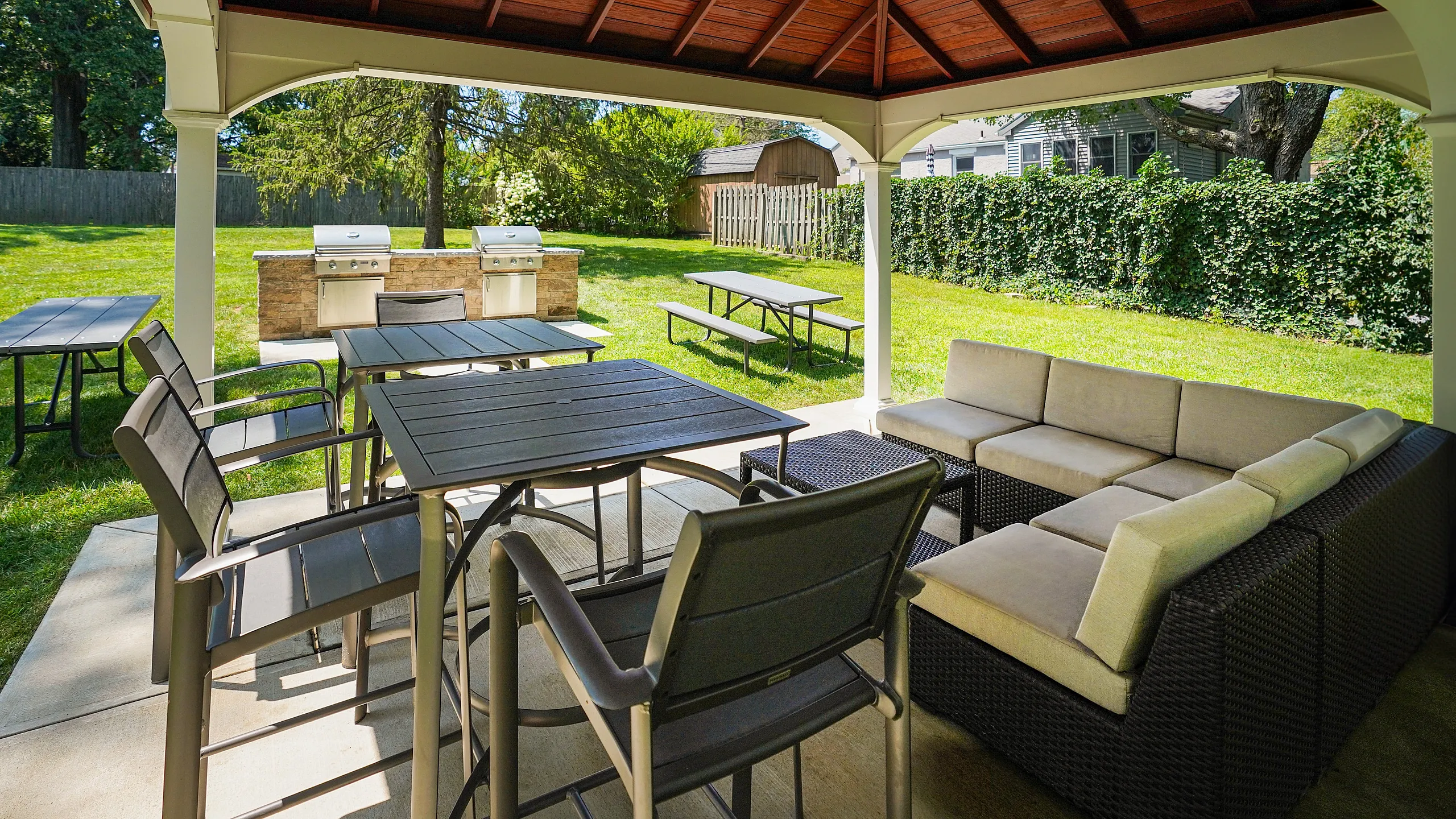 Charming outdoor patio featuring a cozy seating area under a stylish gazebo, perfect for entertaining with built-in grills and picnic tables.
