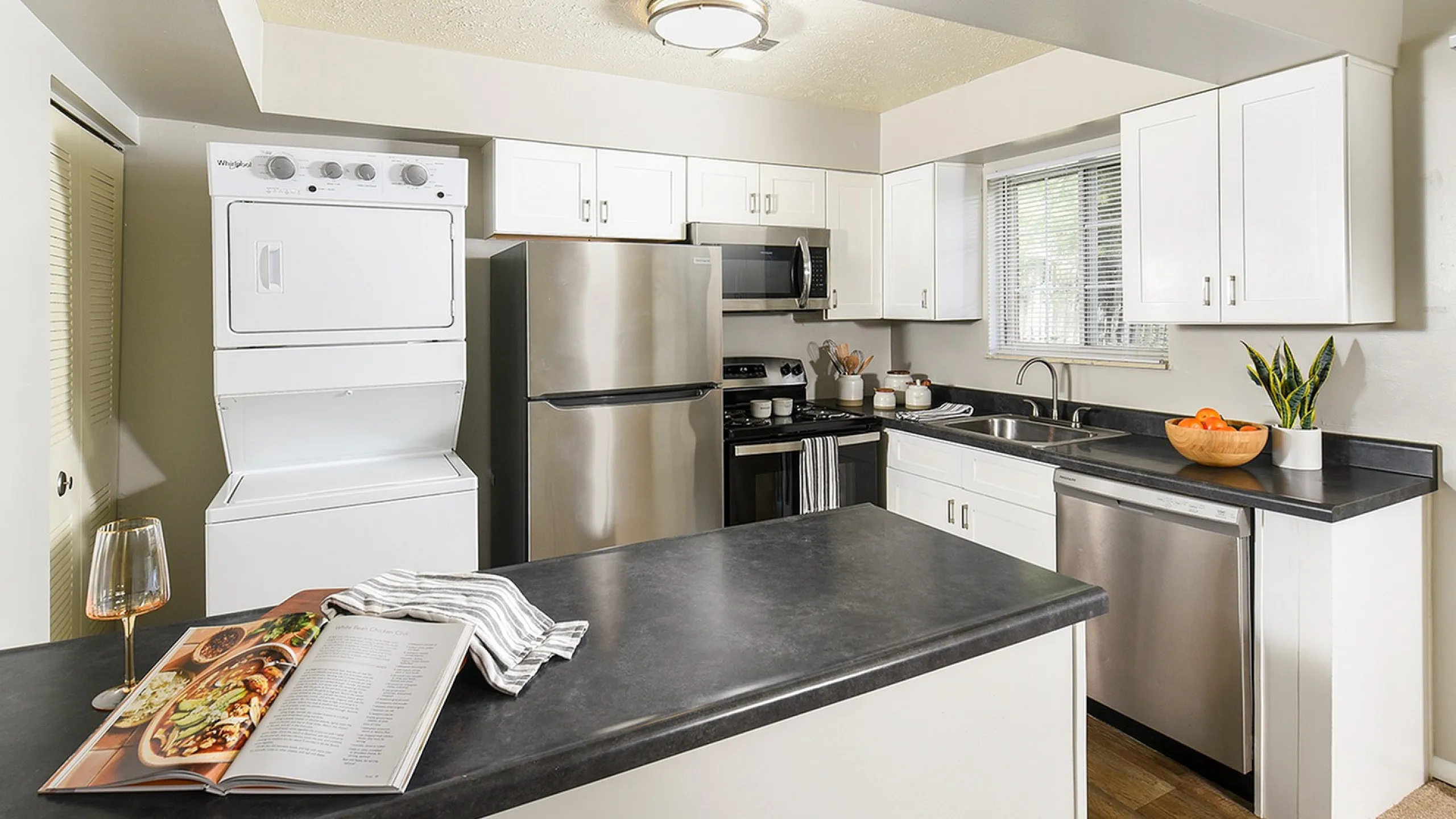 Modern kitchen with sleek stainless steel appliances, white cabinetry, and a stylish open layout featuring a convenient in-unit washer and dryer.