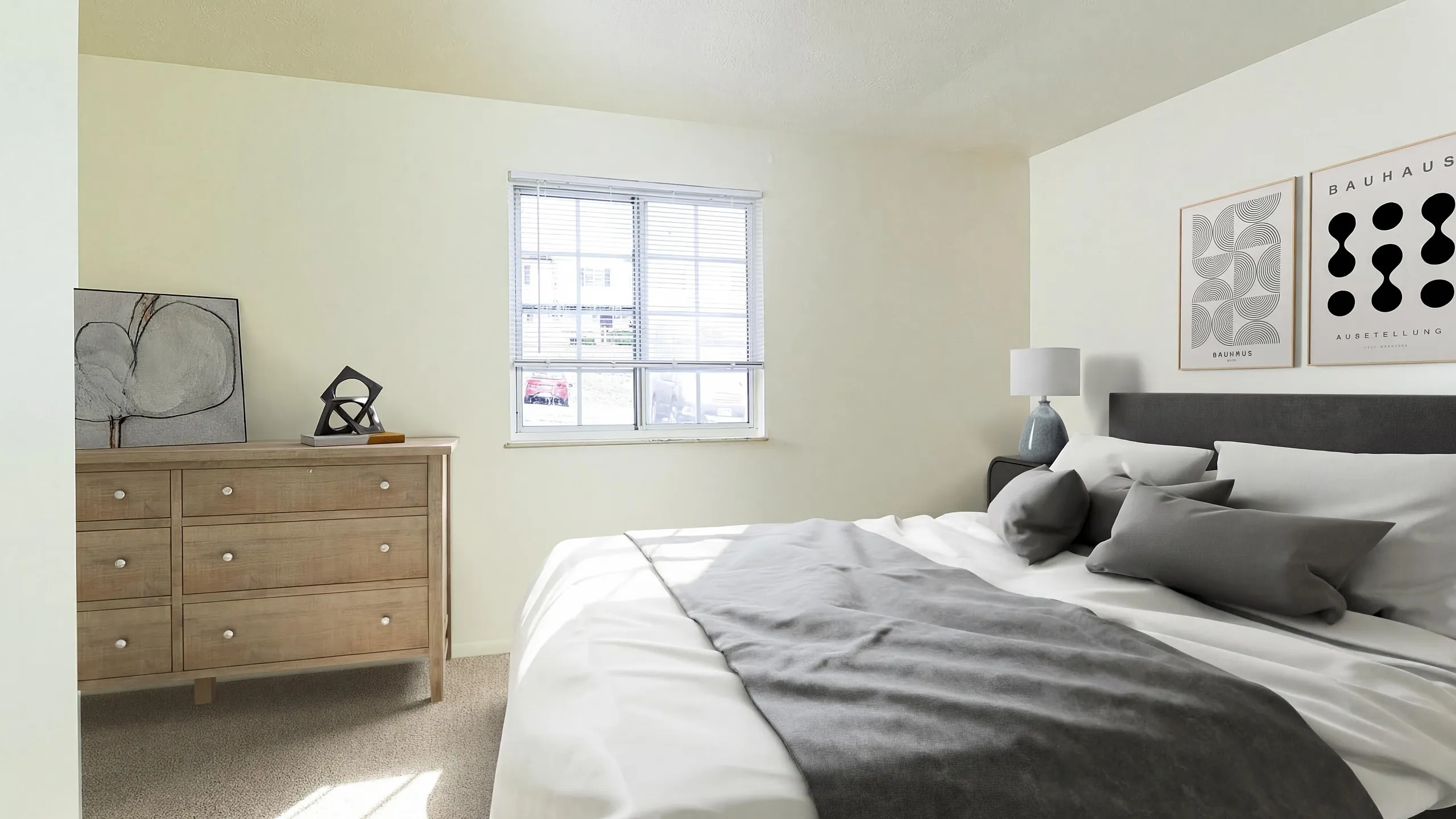 Bright and inviting bedroom with a plush bed, modern decor, and ample natural light through a large window, perfect for serene living.