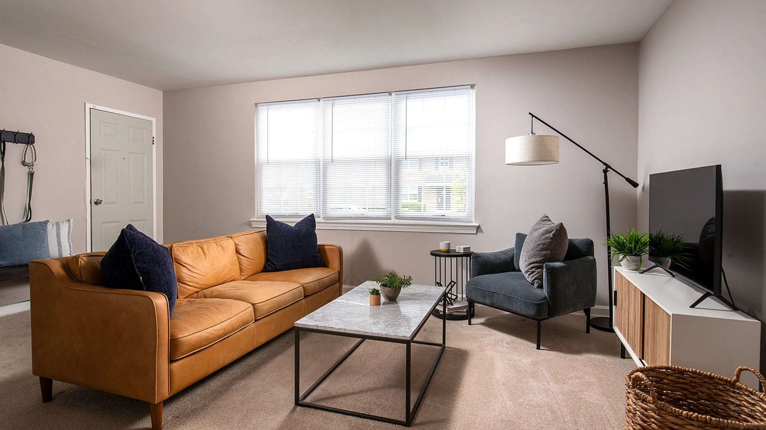Inviting living room with natural light, featuring a cozy leather sofa, sleek modern coffee table, and stylish armchair, perfect for relaxation and entertaining.