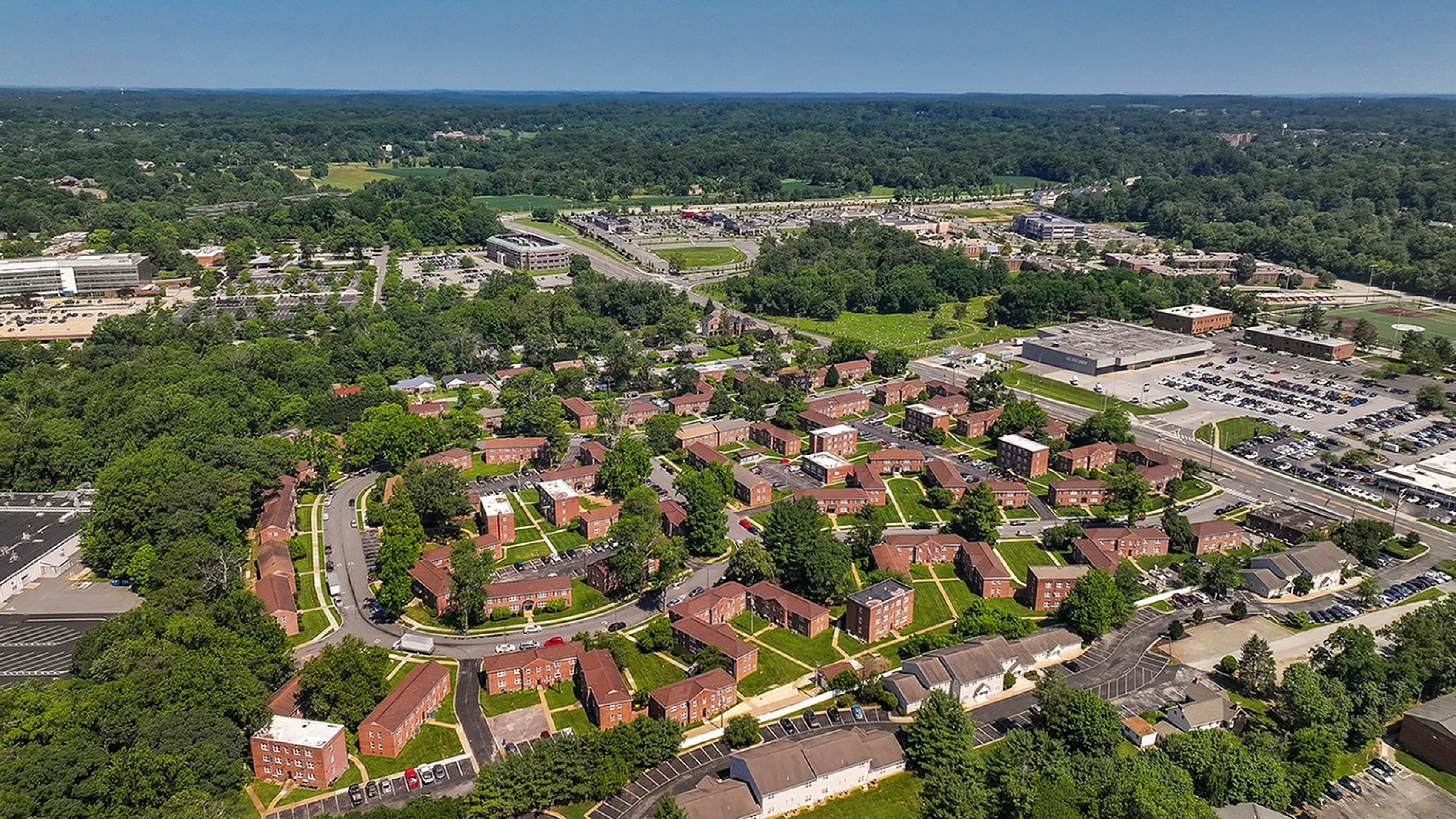 Scenic aerial view of a charming residential community with lush greenery and neatly arranged brick buildings, ideal for family living.